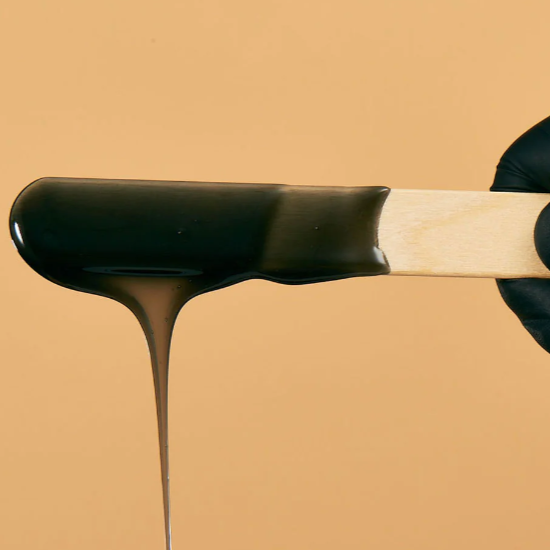Chocolate being poured over a wooden popsicle stick.