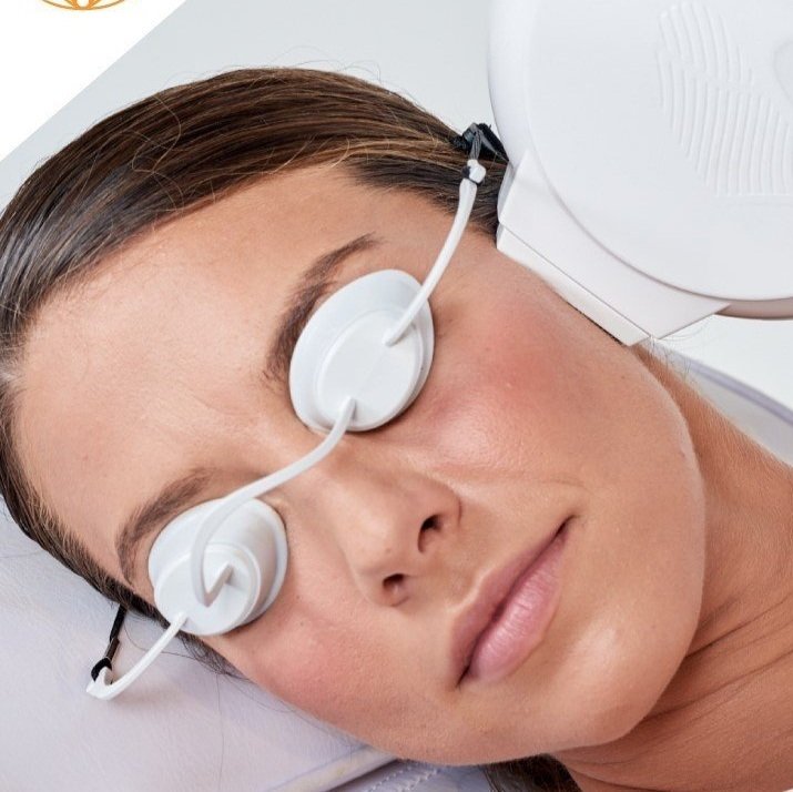 A woman with closed eyes wears a medical eye patch connected to a large medical device.