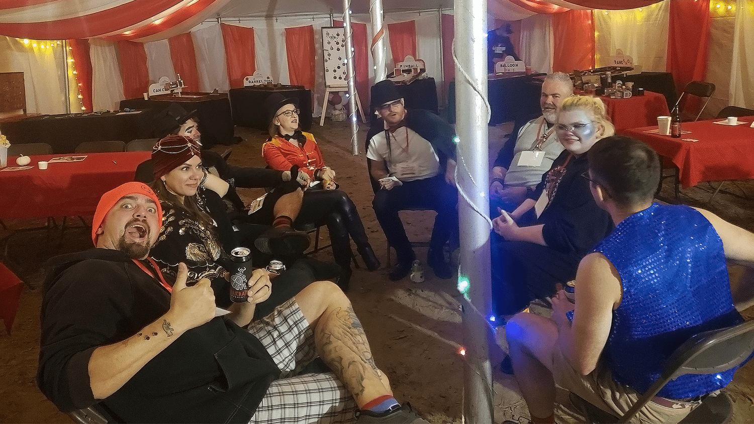 Costumed guests laughing together inside the carnival tent