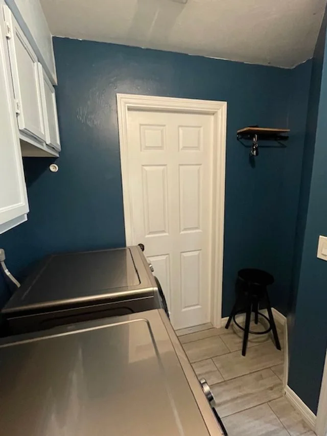 A mixed blue palette was used for the walls and cabinets, plus the addition of shelving + hooks, a small mirror, and a stool helped cheer up the laundry room.