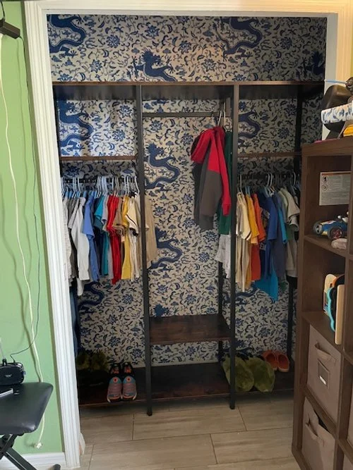 A blue dragon wallpaper was inserted that matched the boys' interest and complemented a blue dresser in the bedroom. The closet feature installation offers a separation of items for both the boys and also provides shelving for organization.
