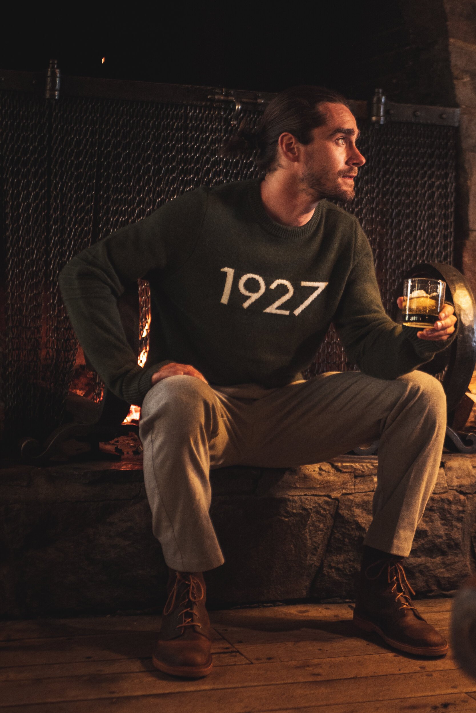 man in front of fireplace holding whiskey