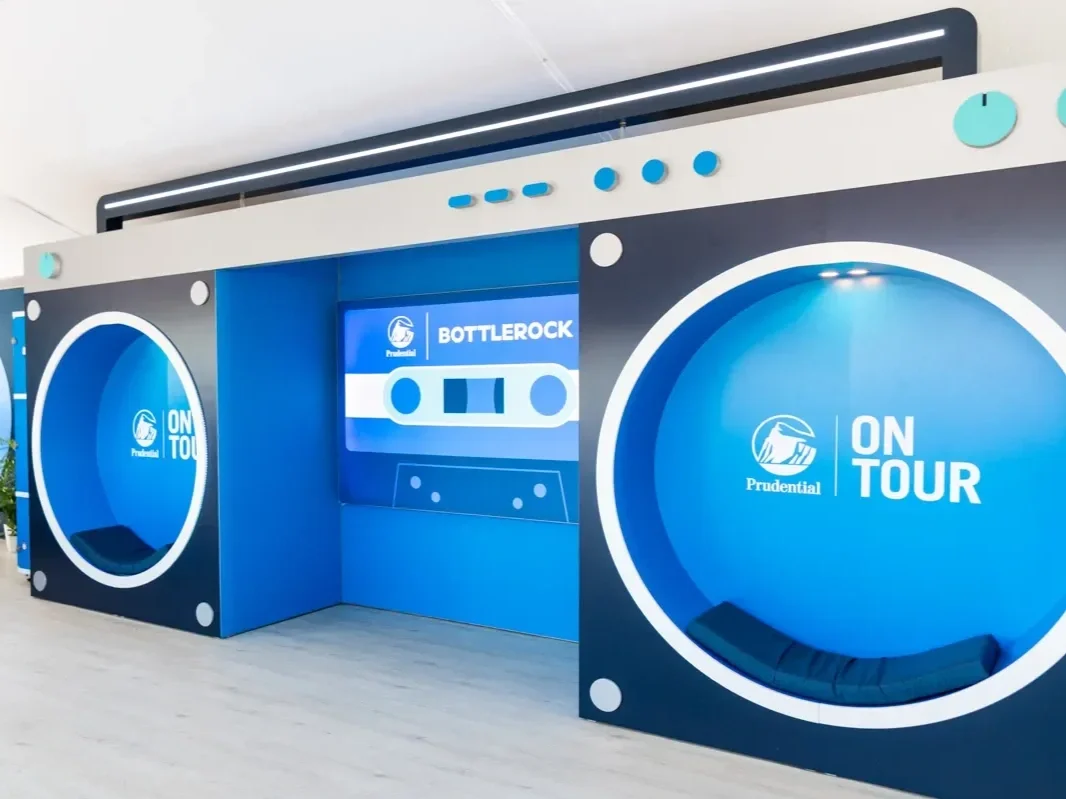 Booth themed as a retro cassette tape with blue and white colors, labeled "Prudential On Tour," featuring a circular seating area and the word "Bottlerock" on a digital screen.