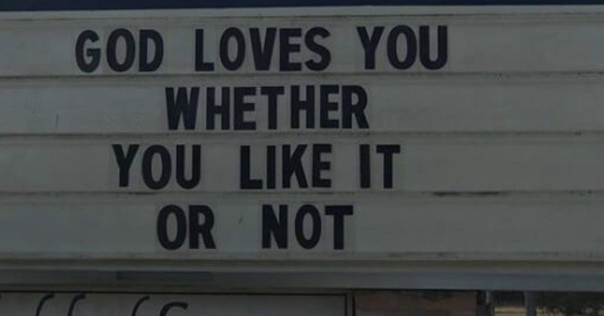 Sign with the message 'God loves you whether you like it or not' displayed in black letters on a white background.