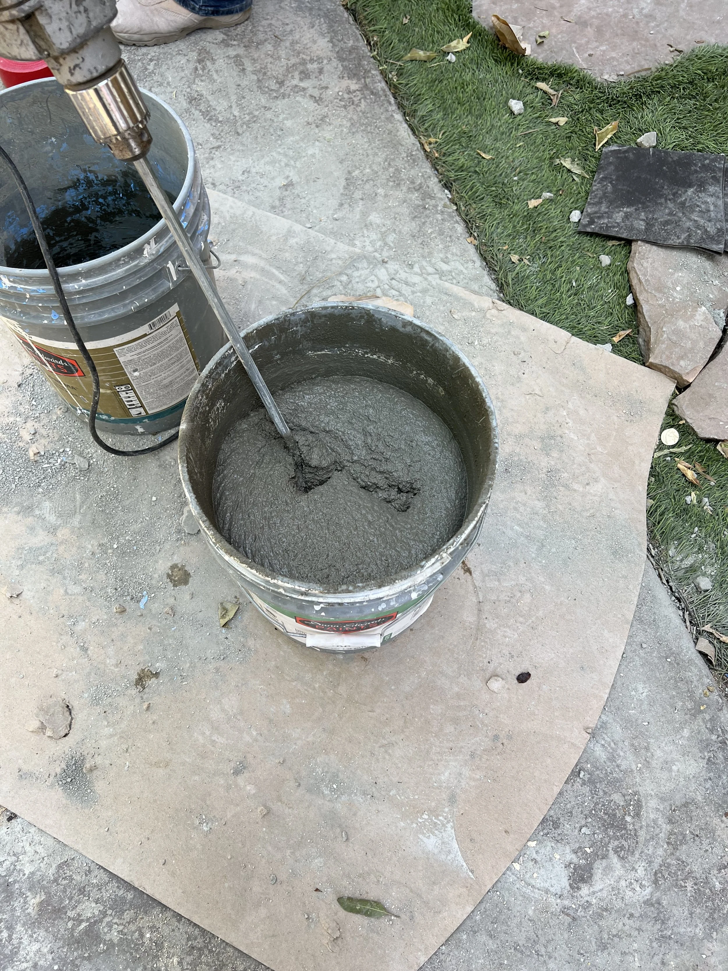 Mixing cement outside on backyard tile floor near grass.