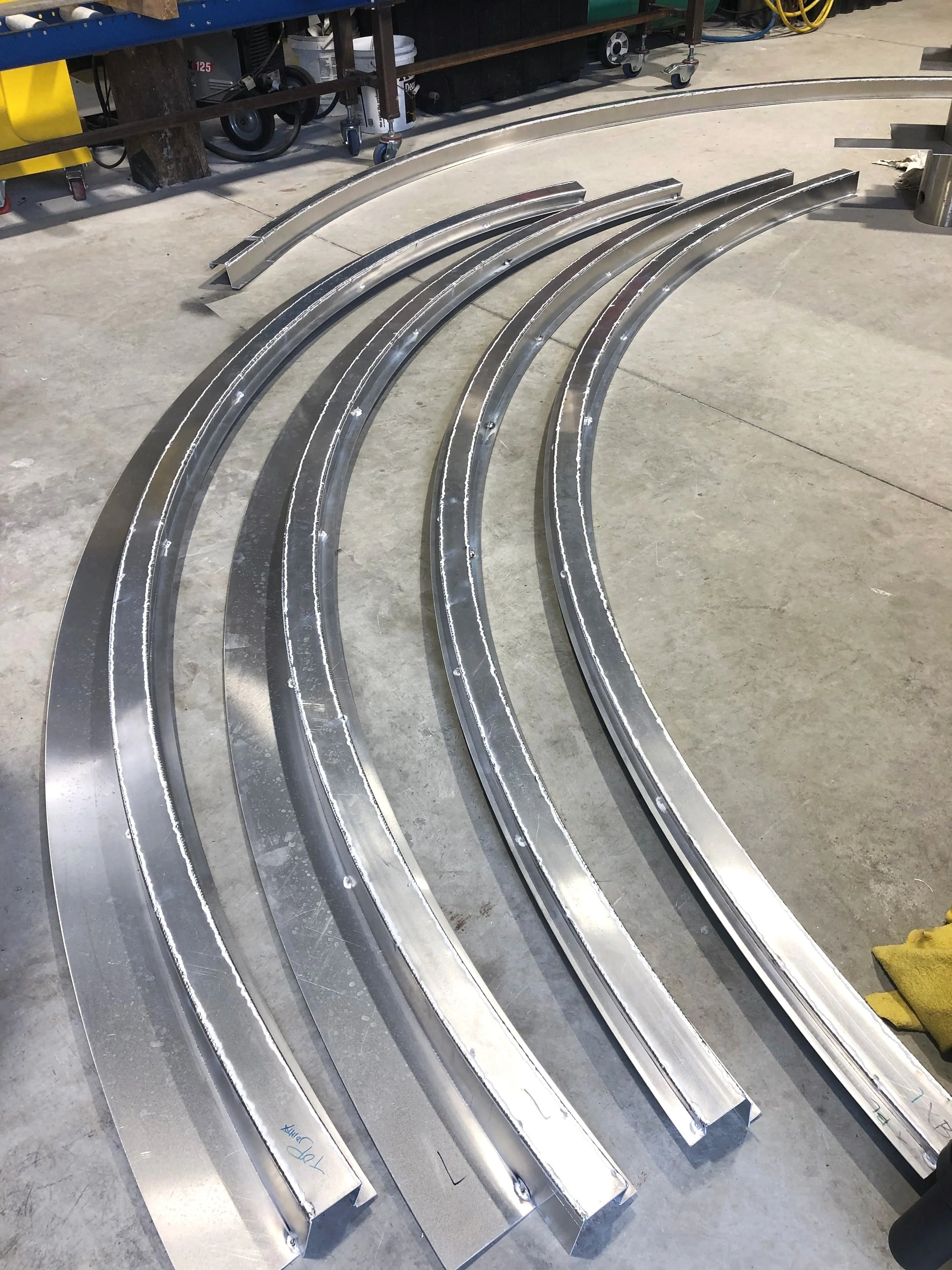 Curved metal beams arranged on a workshop floor