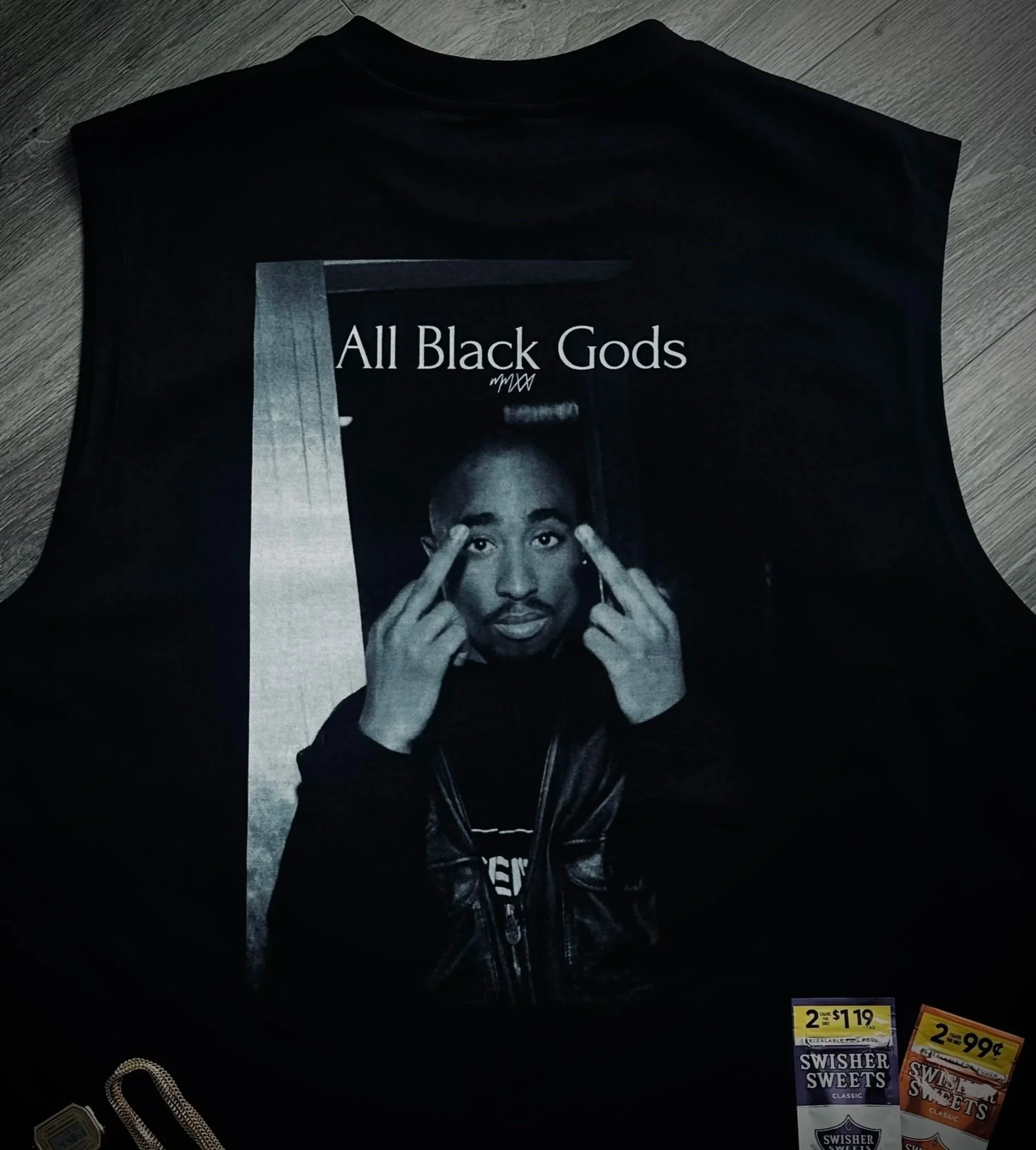 Black sleeveless shirt featuring a black and white photo of a man making a gesture with his hands, with the text "All Black Gods" above the image.