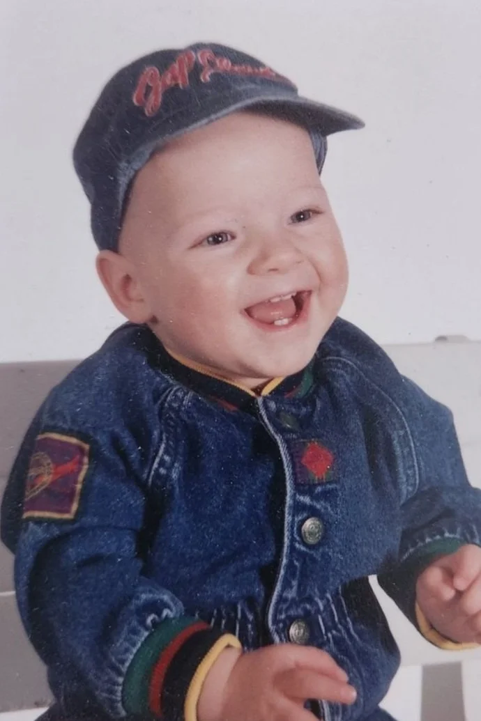 Smiling baby wearing a denim jacket and cap