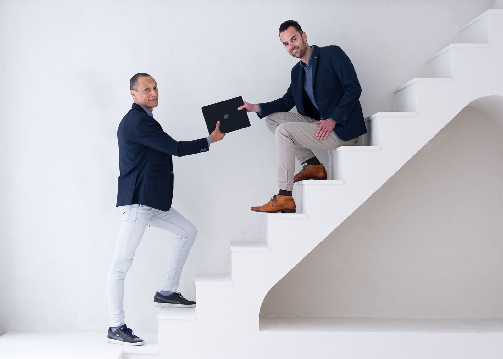 Heren geven elkaar een Microsoft surface laptop foto gemaakt op trap