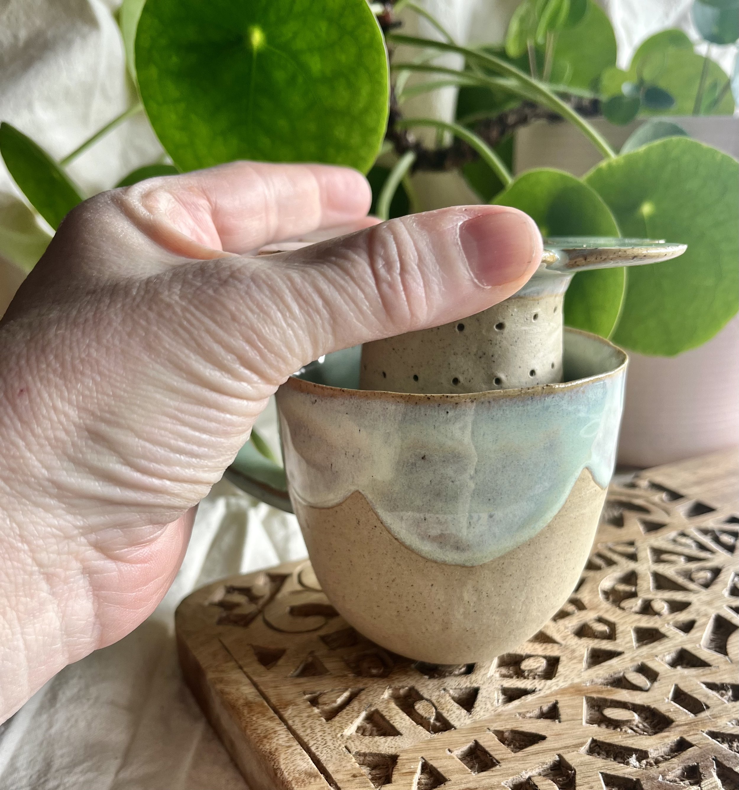 Light green scalloped mug with tea strainer lifted.jpeg