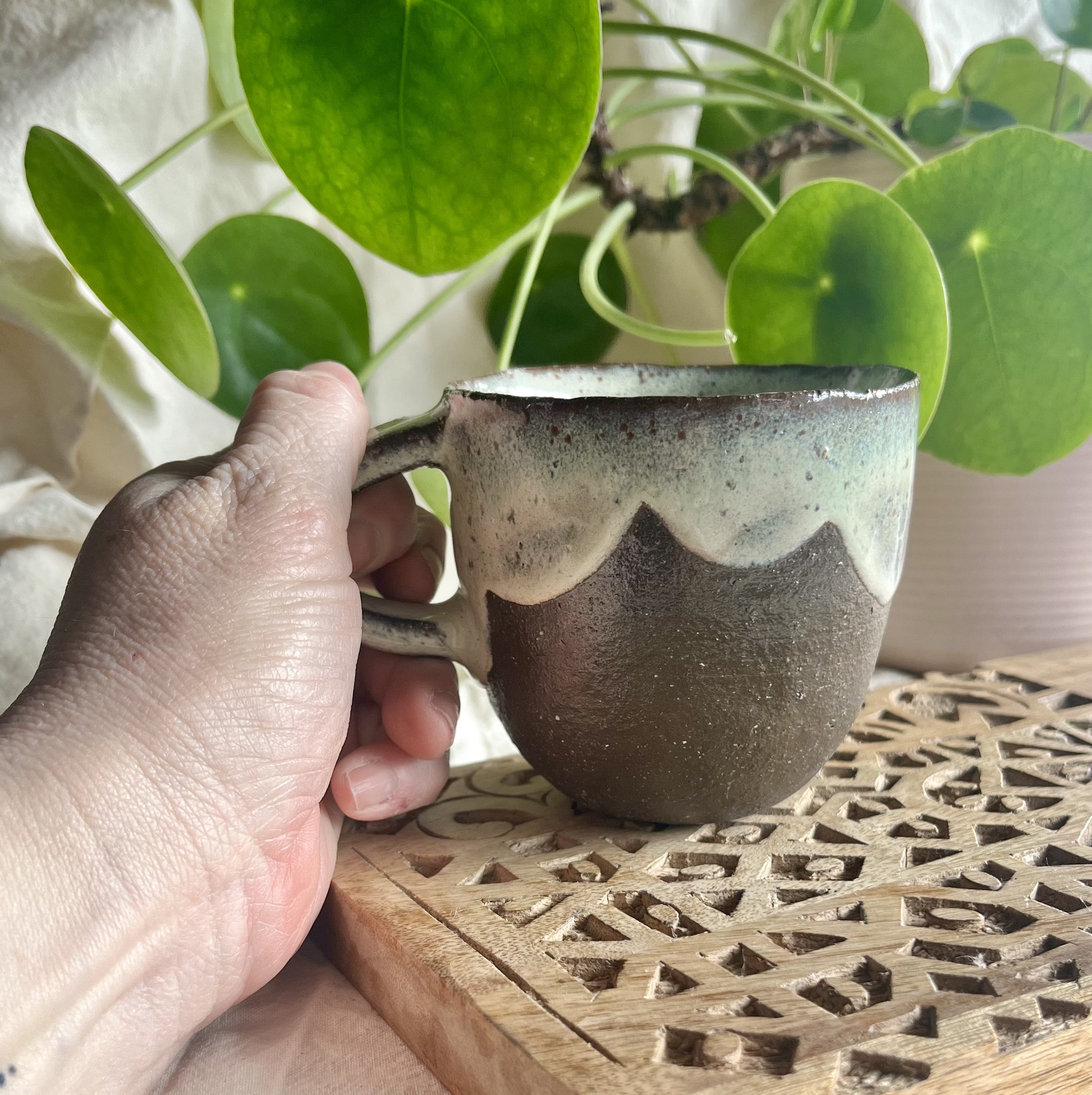 Cream on dark matter scalloped mug 1 in hand view.jpeg