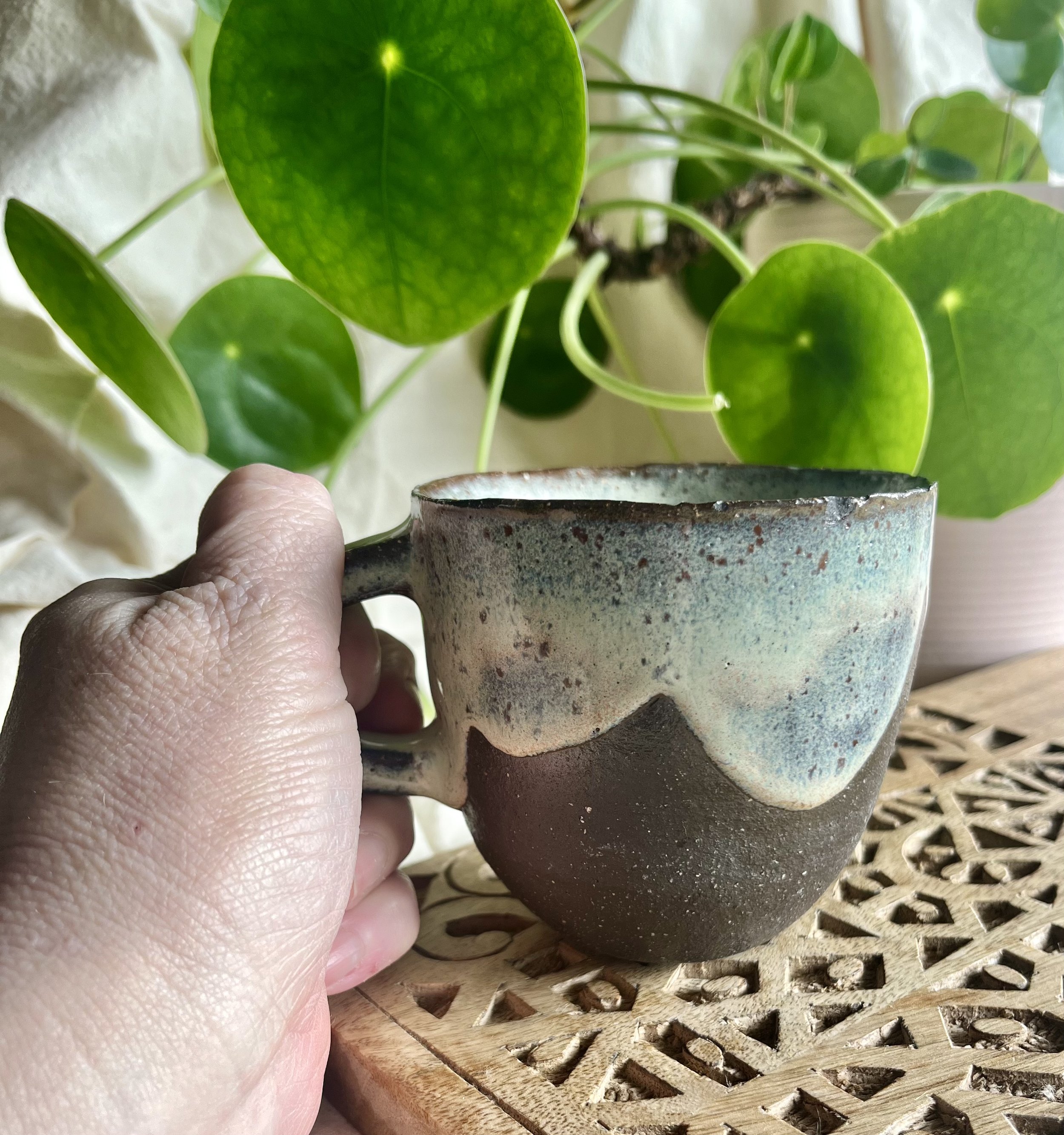 Cream on dark matter scalloped mug 2 in hand view.jpeg