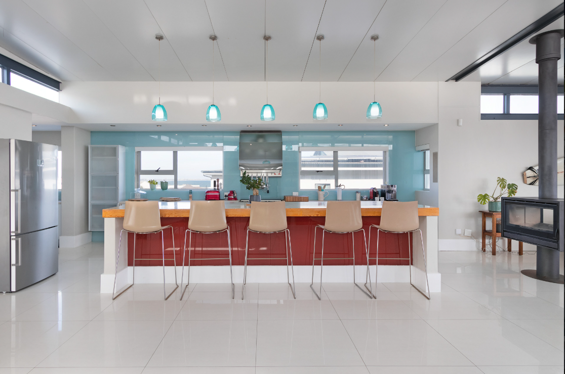 Modern open-concept kitchen with a 4m island, beige bar stools, glass pendant lights, stainless steel refrigerator, and large windows.