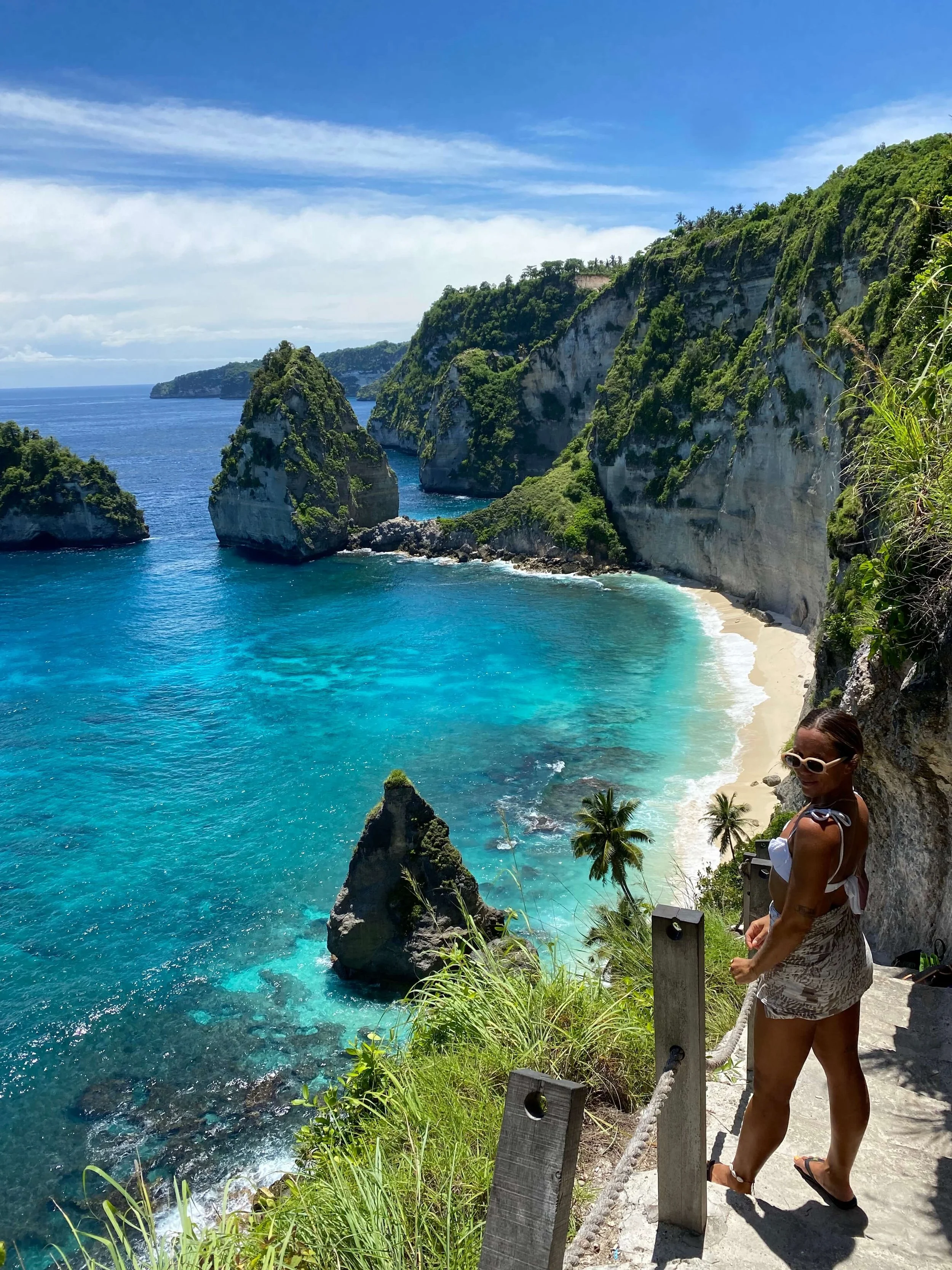 A woman overlooks the dramatic ocean vista, enjoying the scenic view of Nusa Island, Bali.