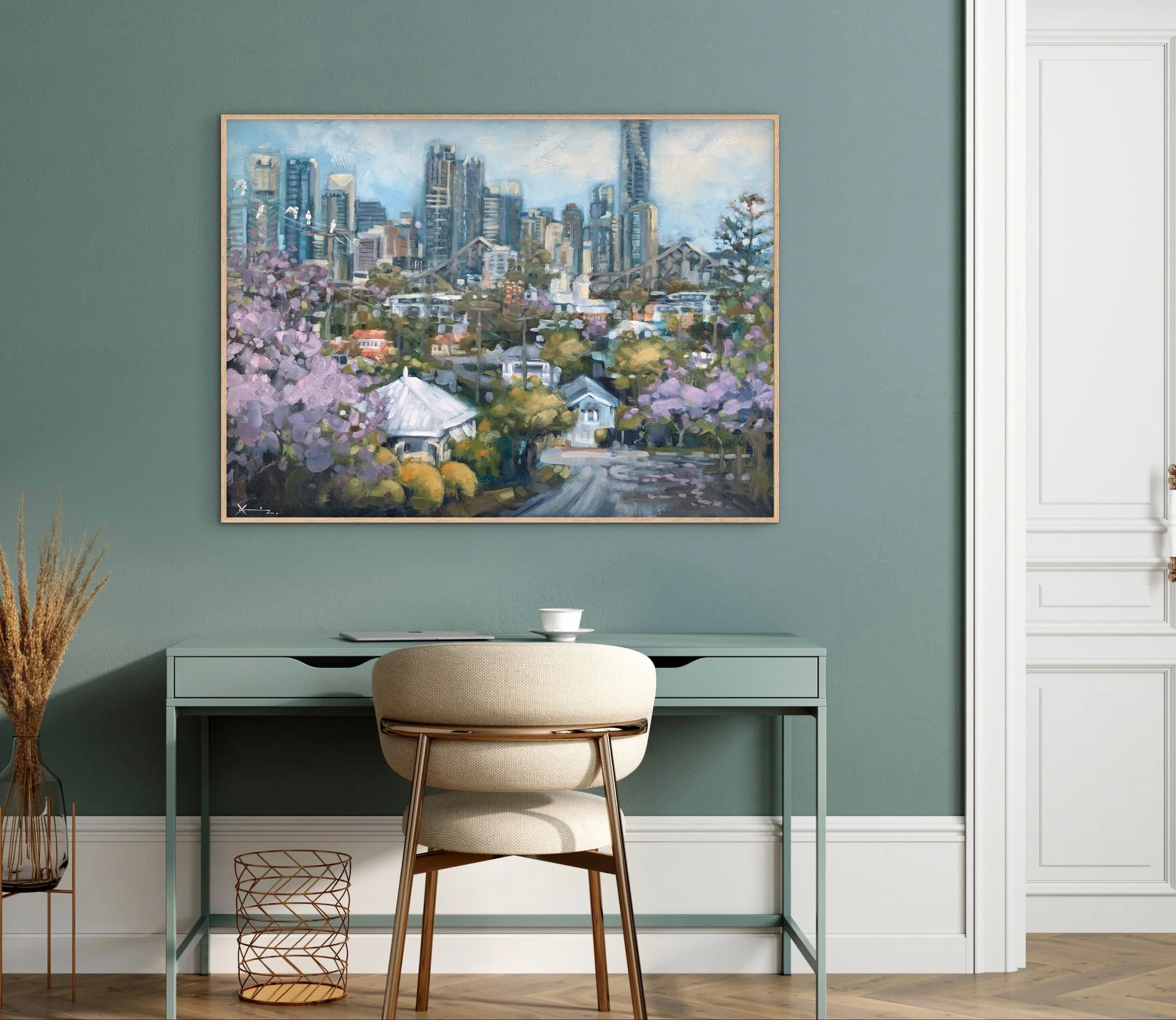 A modern workspace with a light green desk and beige chair in front of a green wall, with a cityscape painting hanging on the wall.