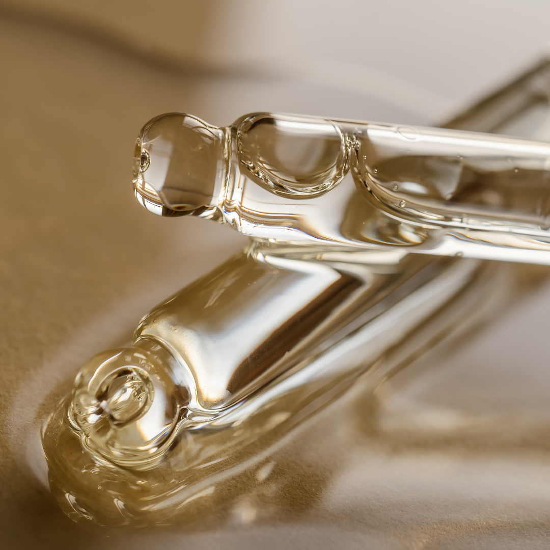 Close-up van een glazen parfumfles met een minimalistisch ontwerp, gelegd op een zachte, beige ondergrond.