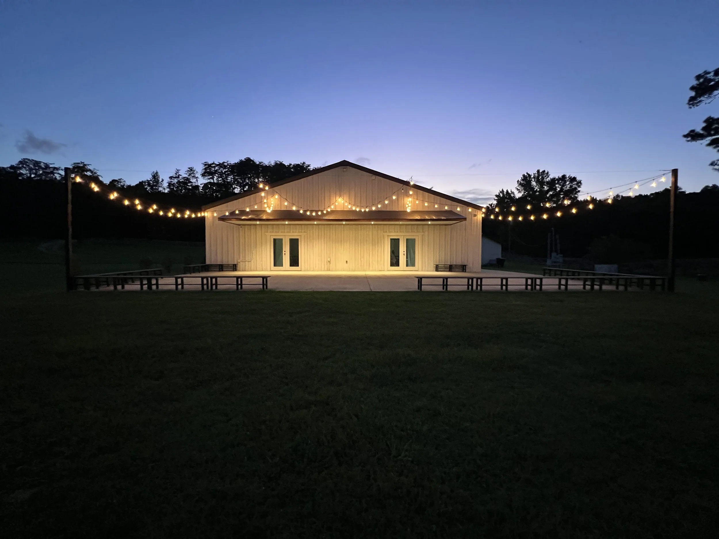 back patio at Alabama wedding venue, Sawyers Cove Farm, featuring romantic cafe lighting under a dusky sky