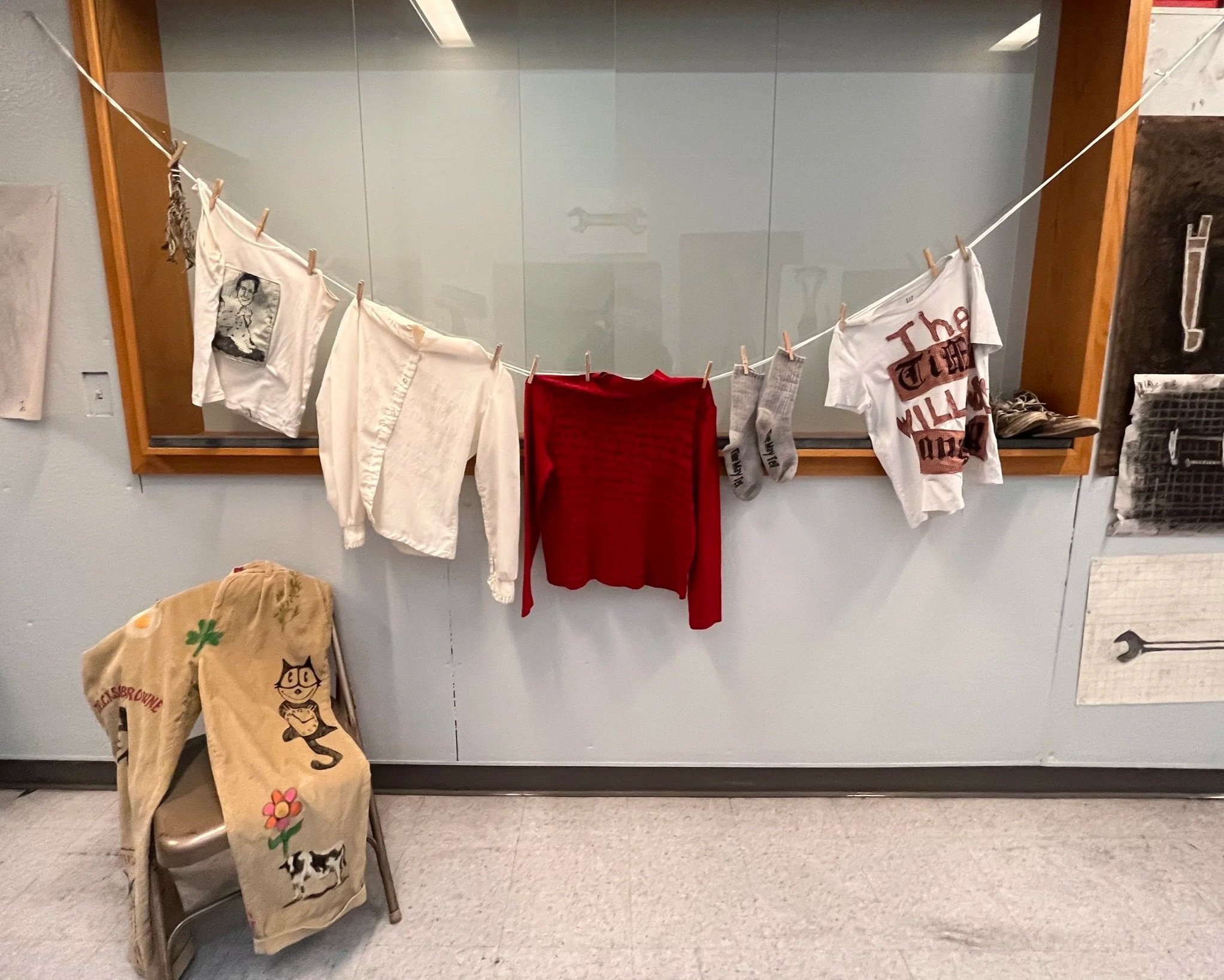 Woolgathering. From left: senior corduroys, bundle of dried sage, quilted tank with ink drawing on bedsheet, inked poem on polyester shirt, inked poem on red turtleneck, socks with printed words "Time May Tell," quilted shirt with words "The Time Wil