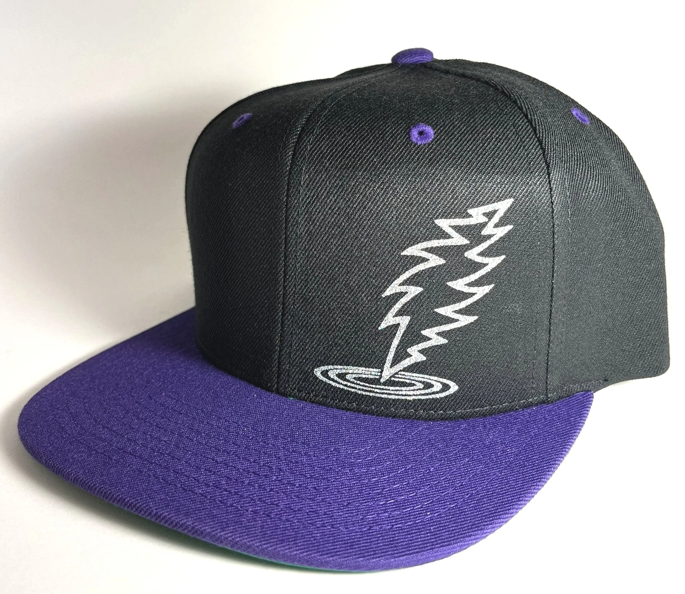 Black and purple snapback hat with a glitter Silver Dancin' bolt with ripple.