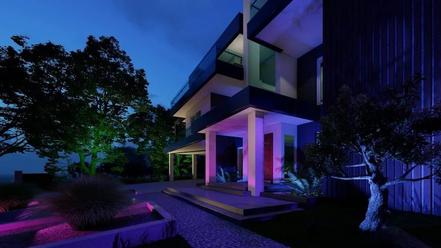 Backyard patio and landscaping illuminated by soft green, pink, and blue outdoor lighting fixtures