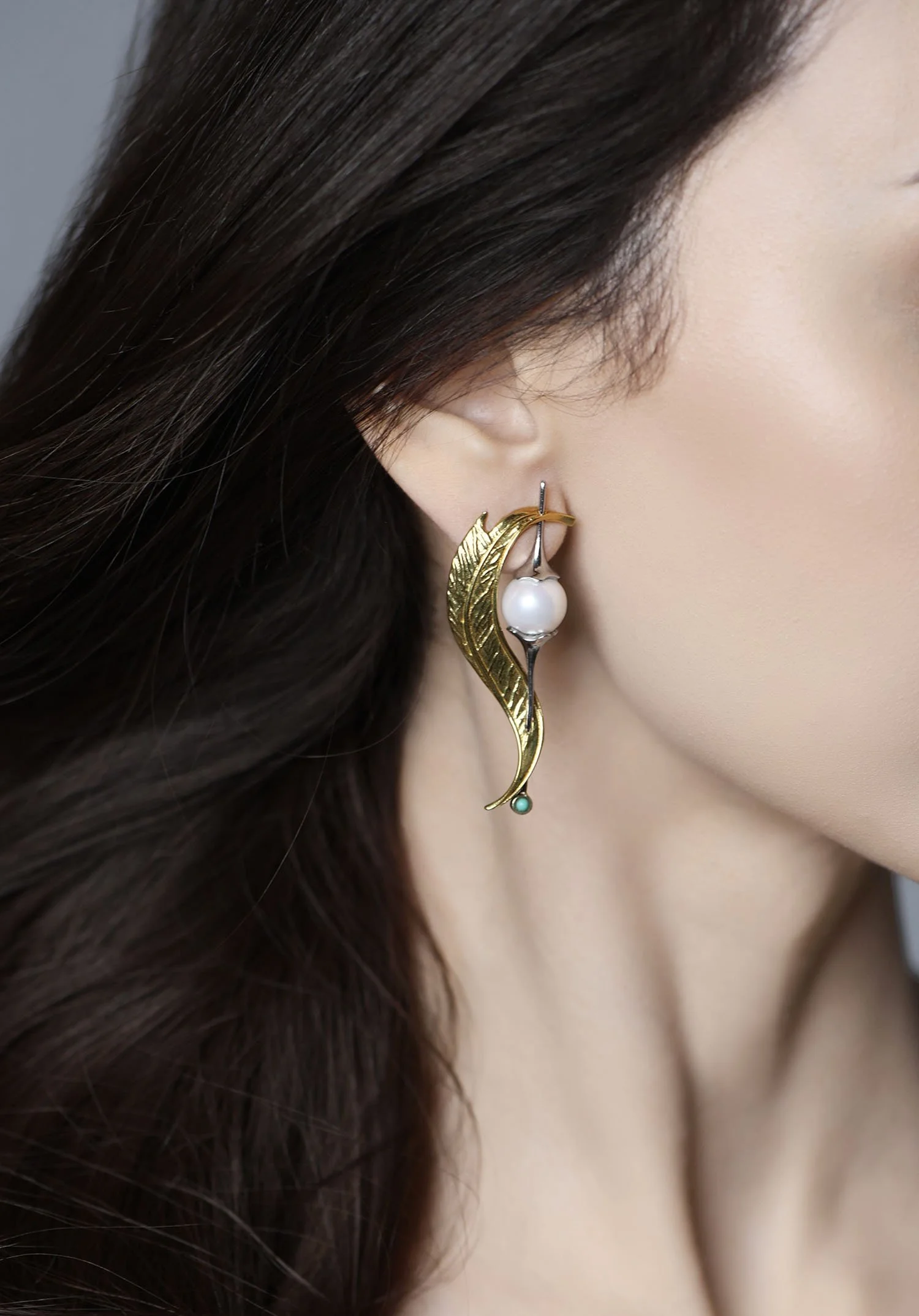 Close-up on-ear view of the Whisper Leaf 14K gold leaf-shaped earring with a white cultured pearl and turquoise accent