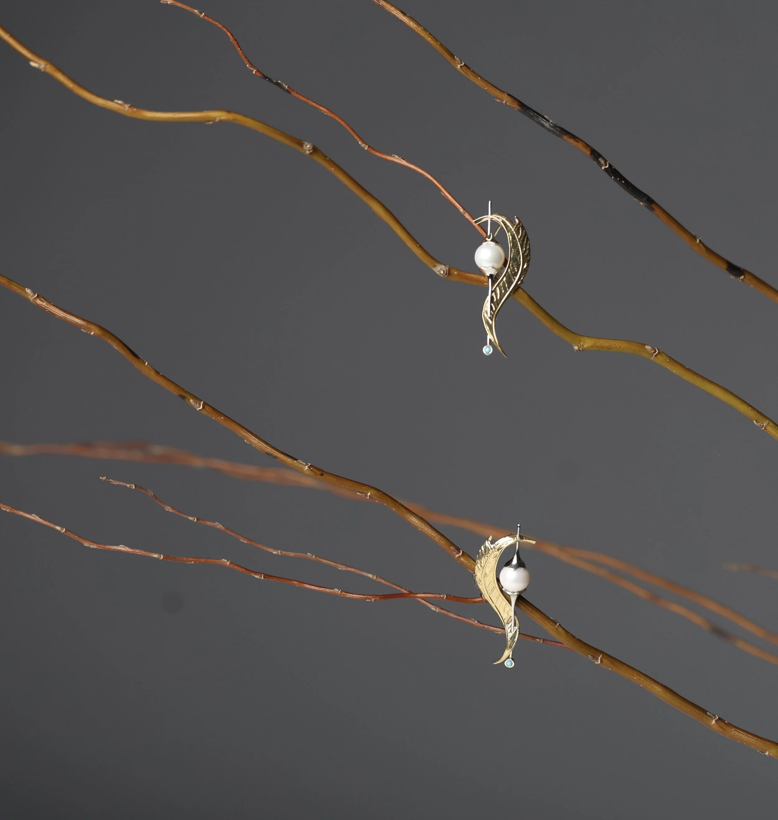 Whisper Leaf 14K gold leaf-shaped earrings with white cultured pearls and turquoise accents displayed on bare branches