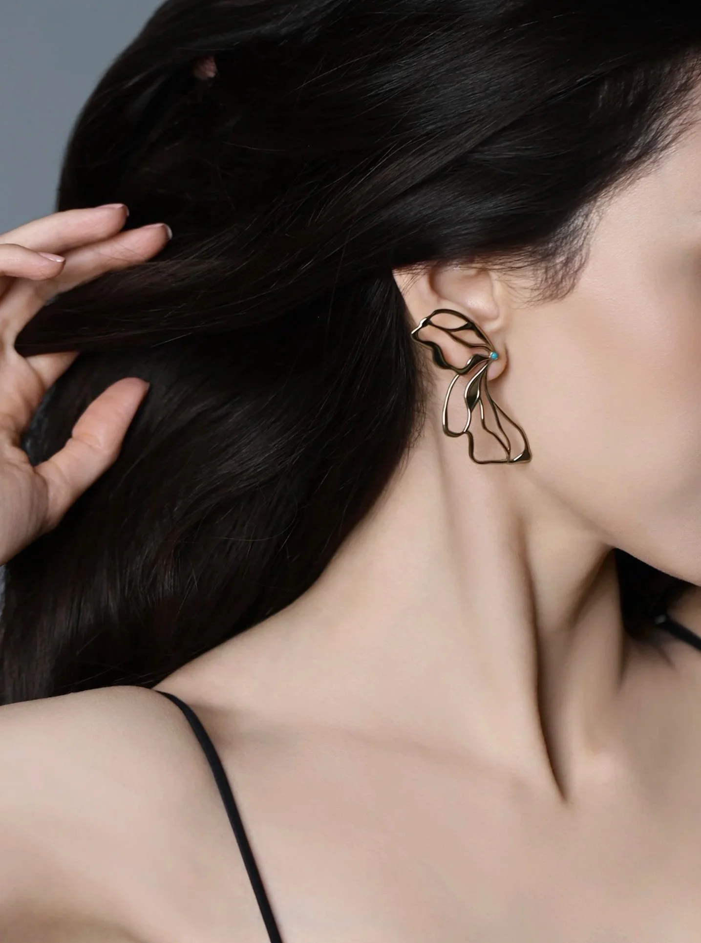 Side-profile close-up of a model wearing the Hana 14K gold butterfly earring with openwork wings and a turquoise accent