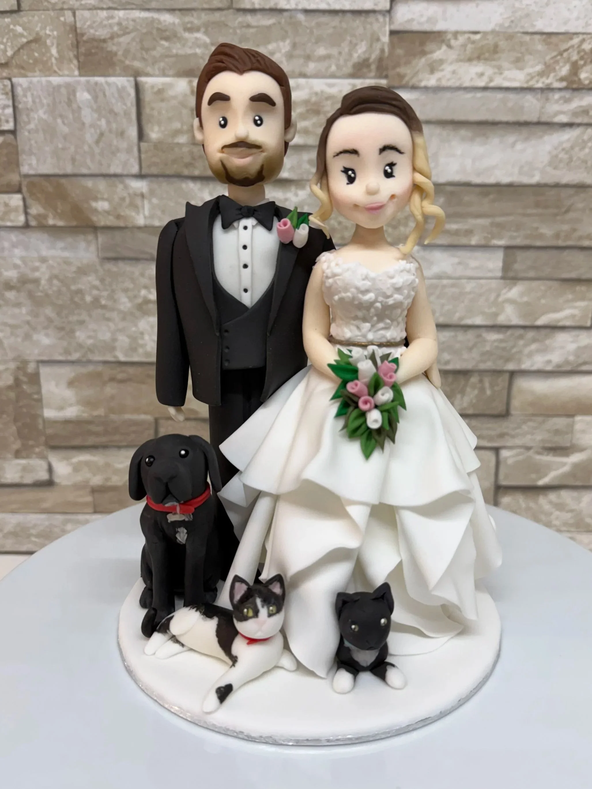 Bride and groom cake figurine with spaniel dog and two cats at the bottom