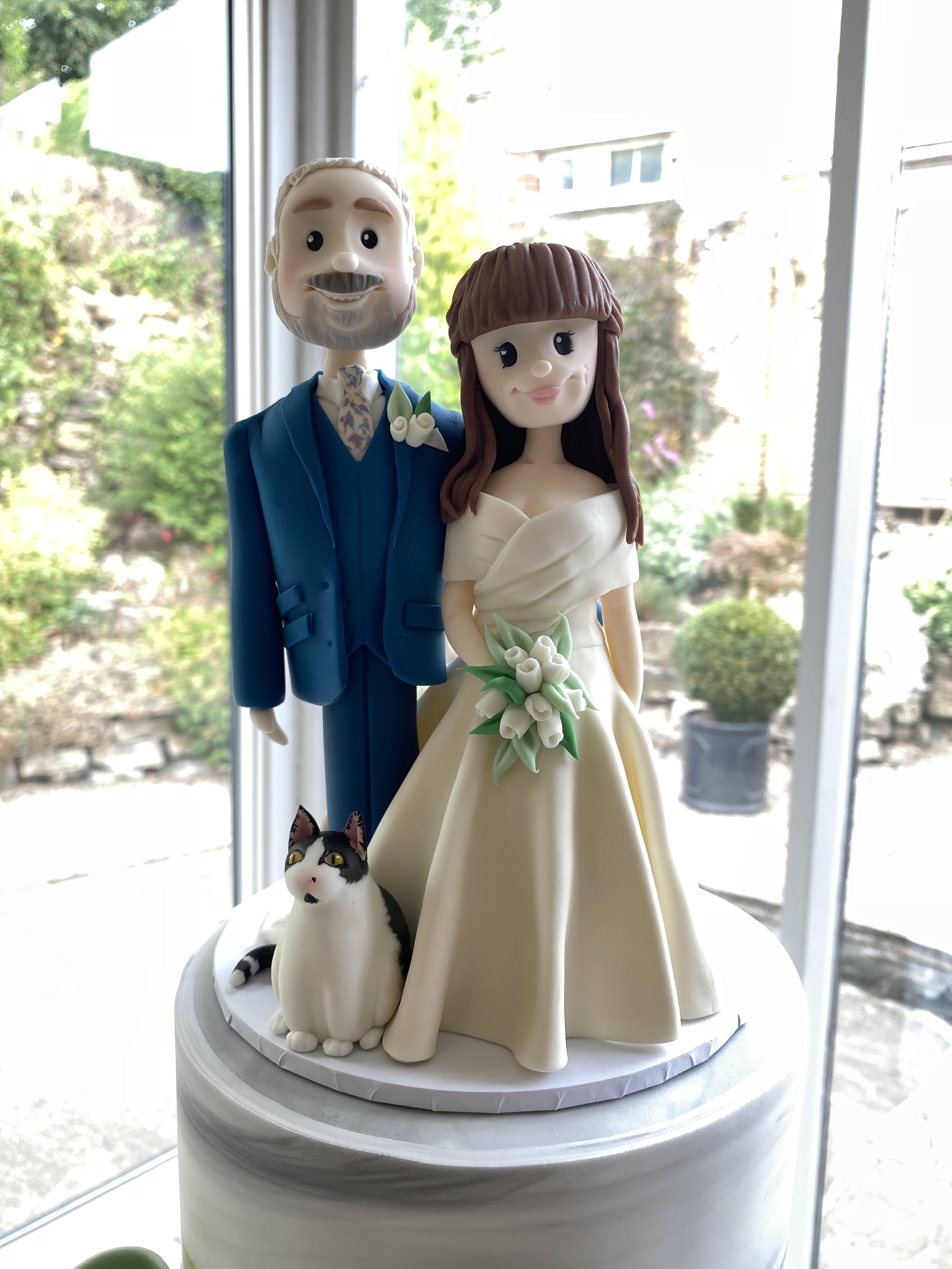 Bride and groom cake topper with pet cat at the base