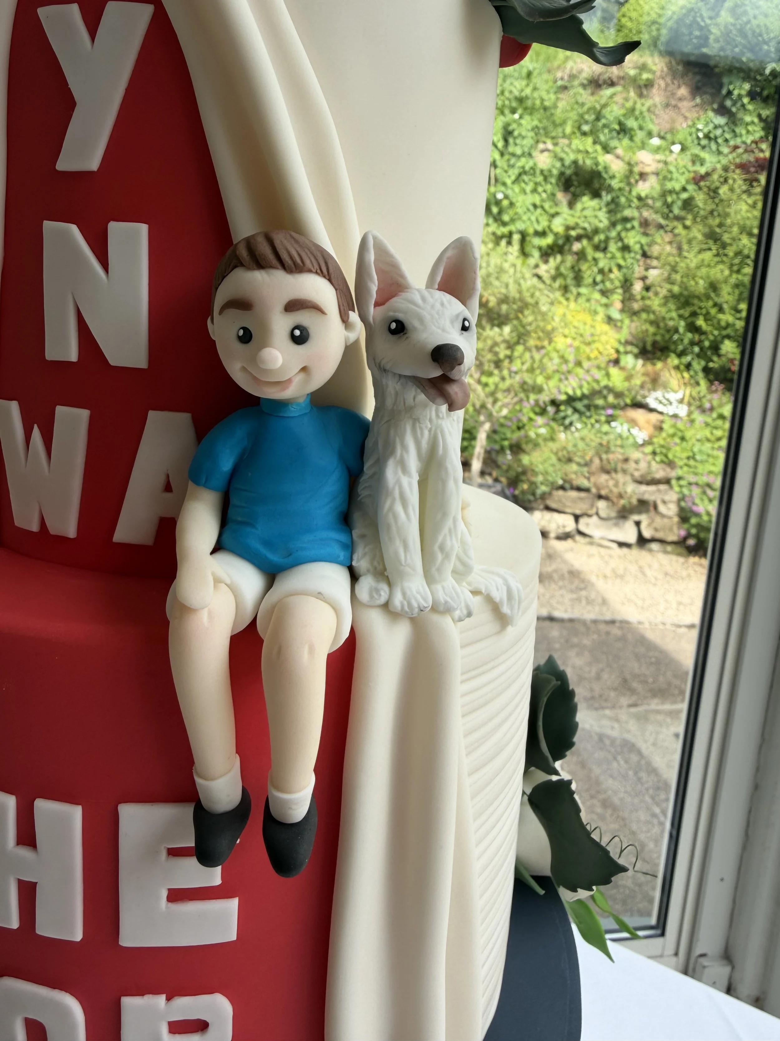 Young boy and white dog cake figurine seated on the edge of a wedding cake
