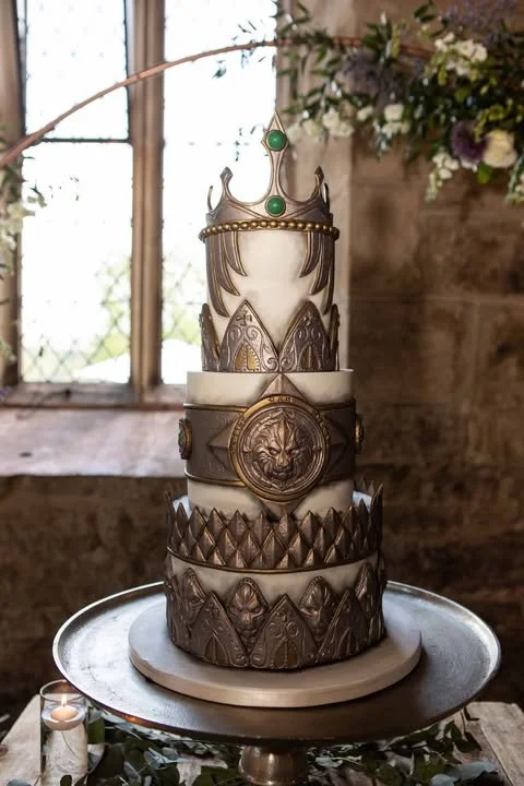 World of Warcraft inspired three tier wedding cake. With metal effect embellishments and crown topper, set up in the Medieval chapel at The Priests House