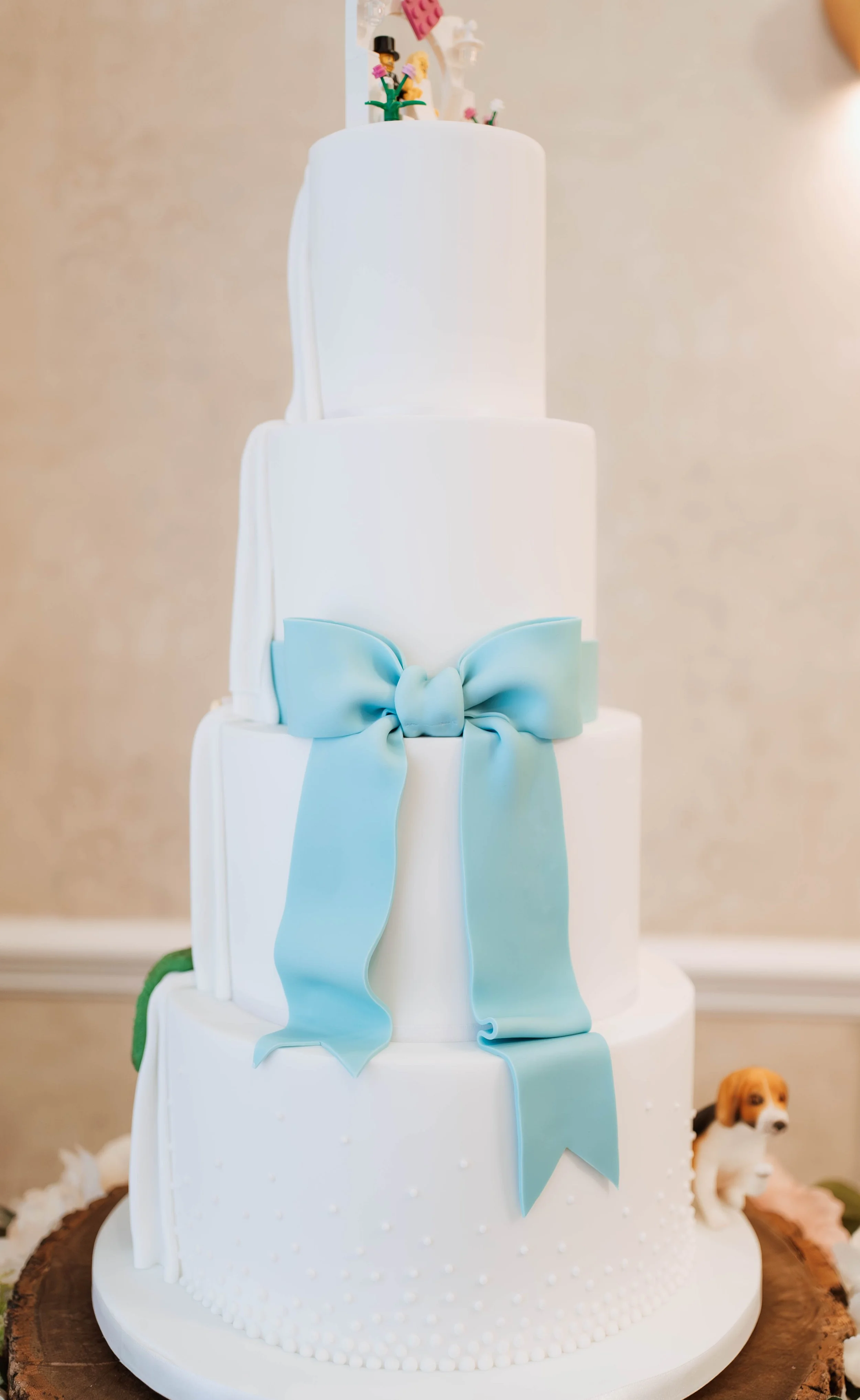 Four tier white wedding cake with blue sugar bow