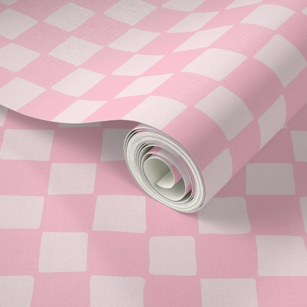 A roll of pink wrapping paper with a white checkered pattern, partially unrolled showing the pattern on the surface.