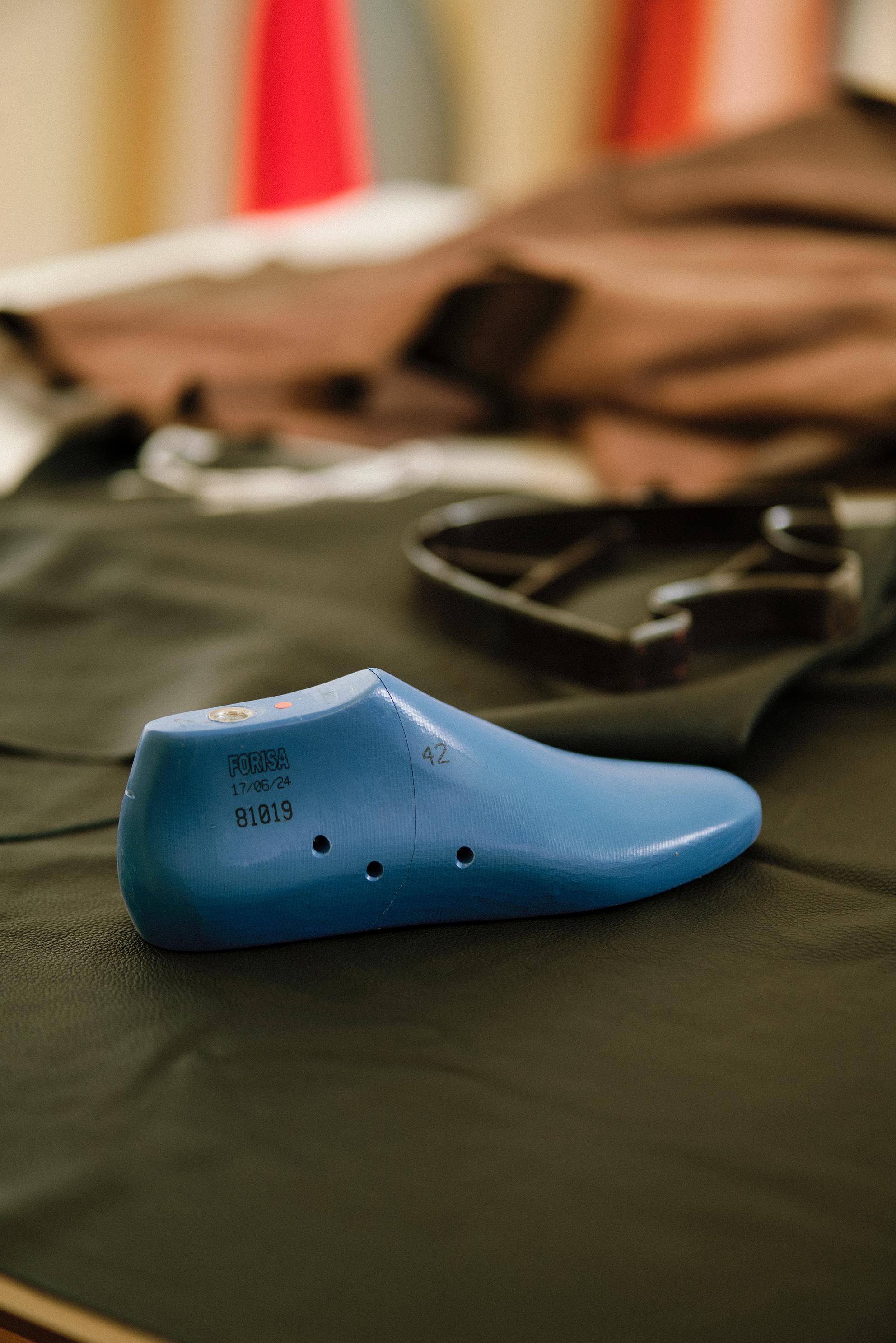 A blue orthopedic prosthetic foot with markings and numbers, placed on a dark surface with bags and other items in the background.