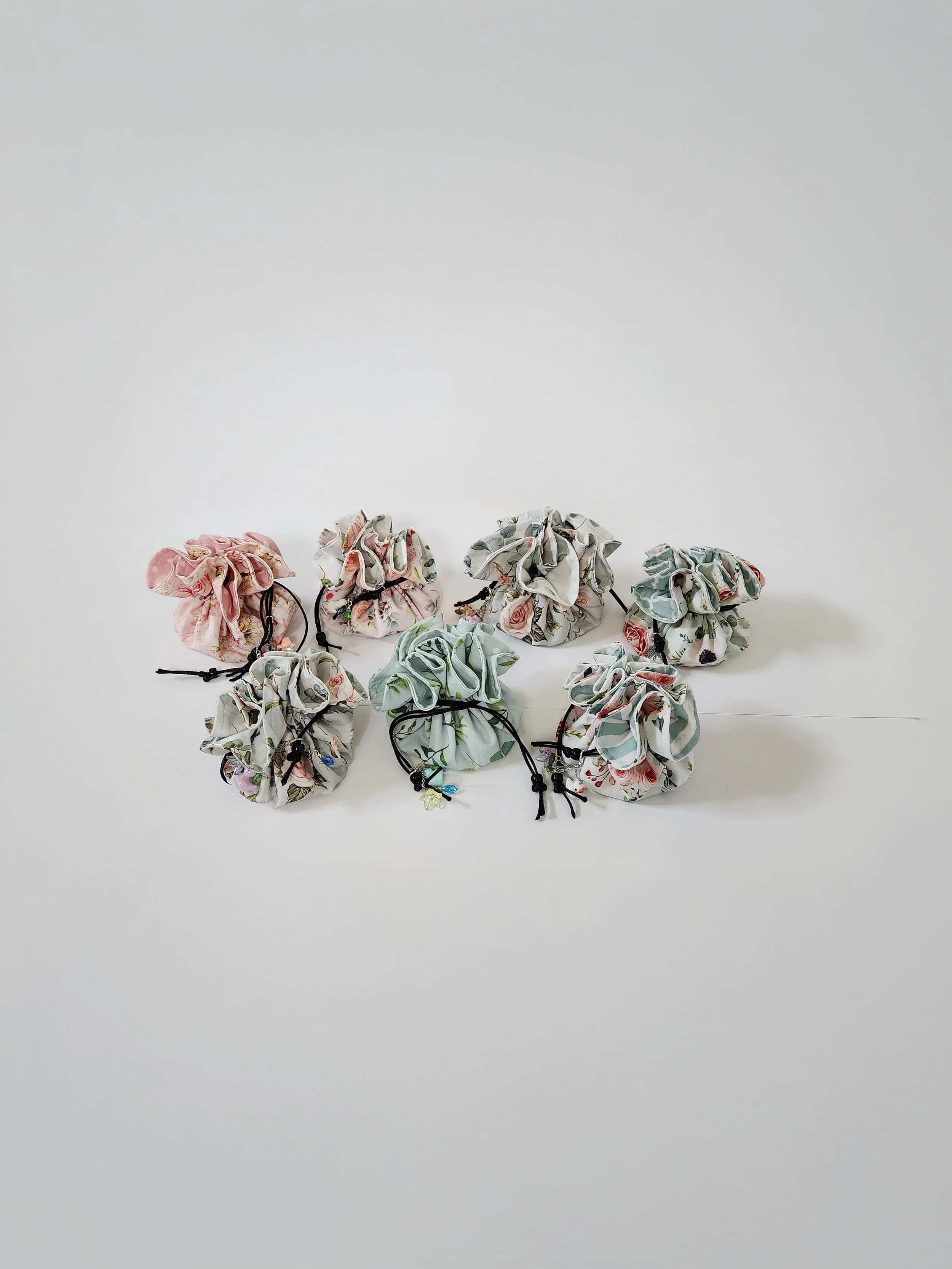 Gathered fabric scrunchies with floral patterns and black hair ties on a white surface against a plain white background.