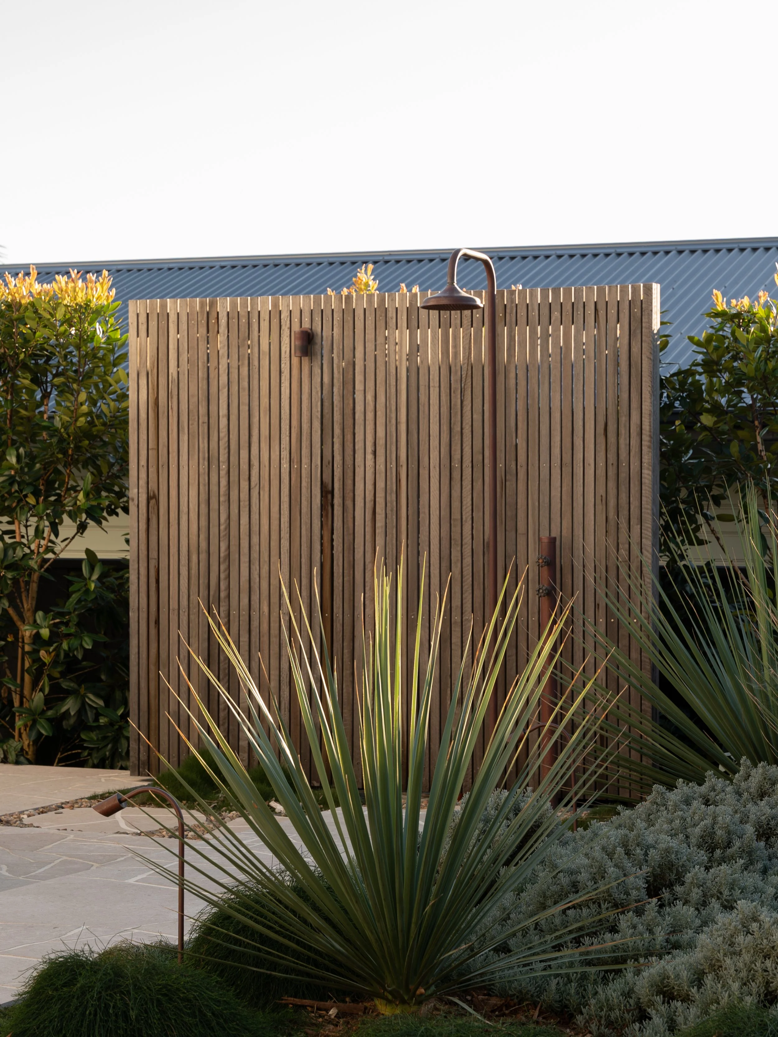 Custom outdoor shower with timber privacy screen and lush planting in a Central Coast landscape design.