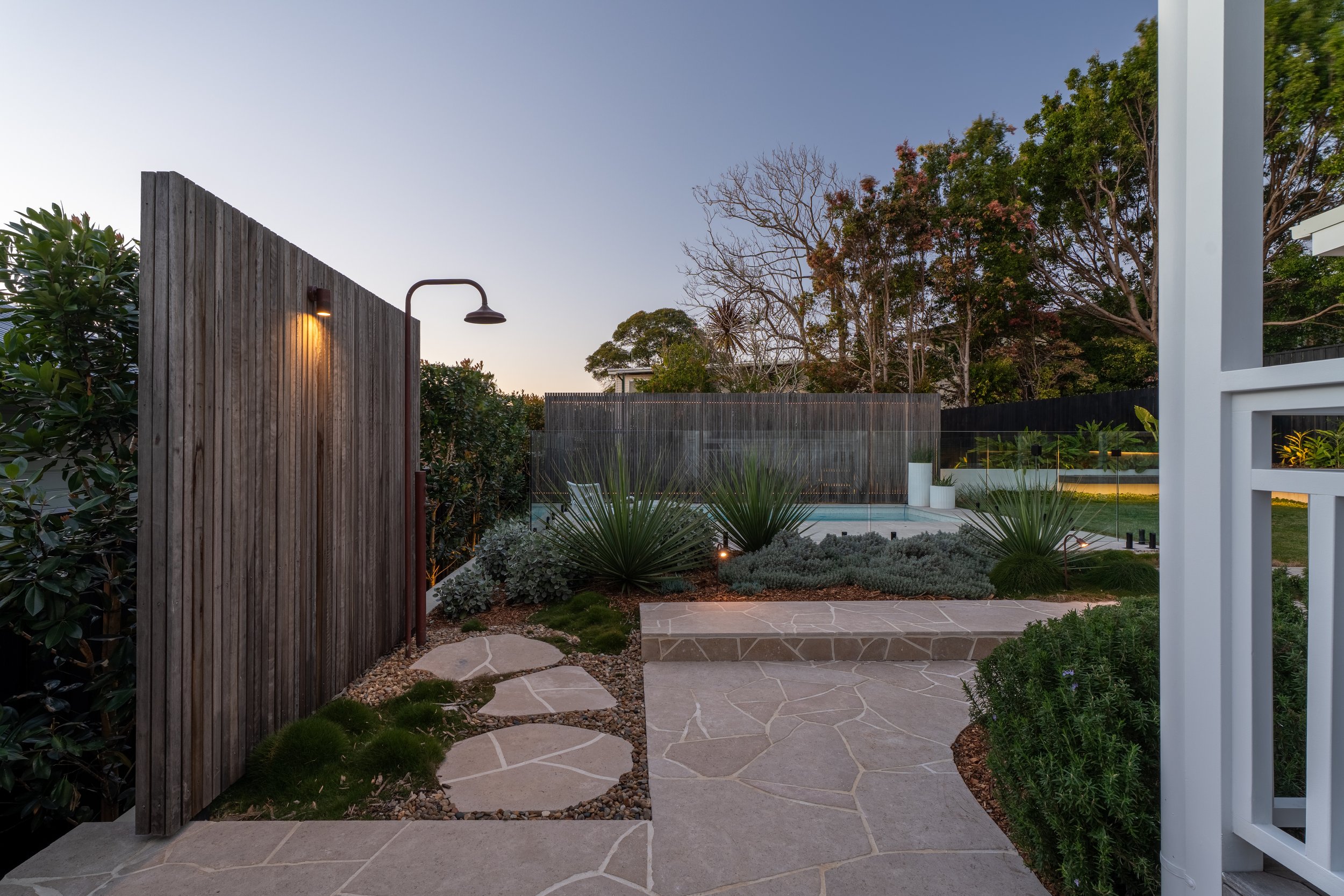 Wamberal landscape and pool design featuring a timber outdoor shower, crazy paving and sculptural planting.
