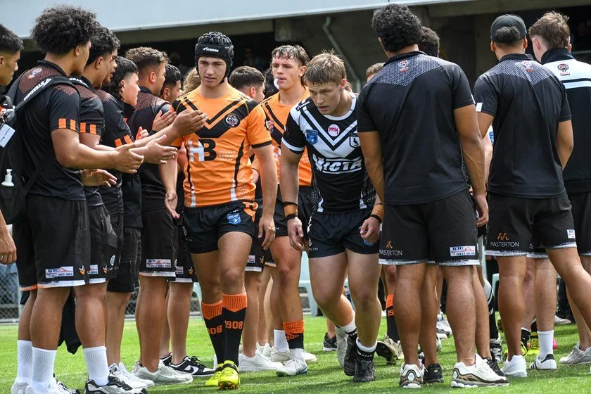 Balmain Tigers players in SG Ball Rugby shaking hands after a match, standing on a rugby league field.