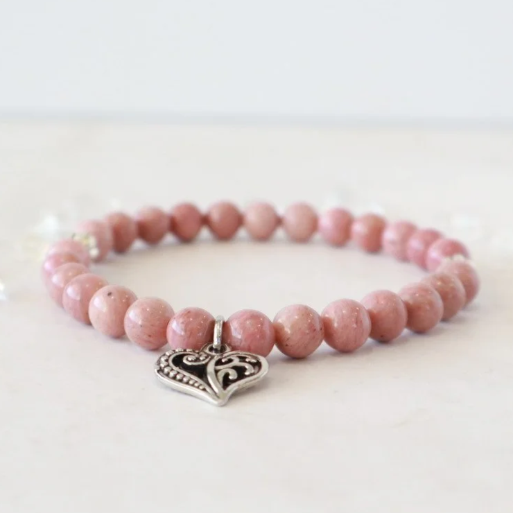 Beaded stretch bracelet made with dusty pink Rhodochrosite beads, silver spacers and a silver filigree charm.
