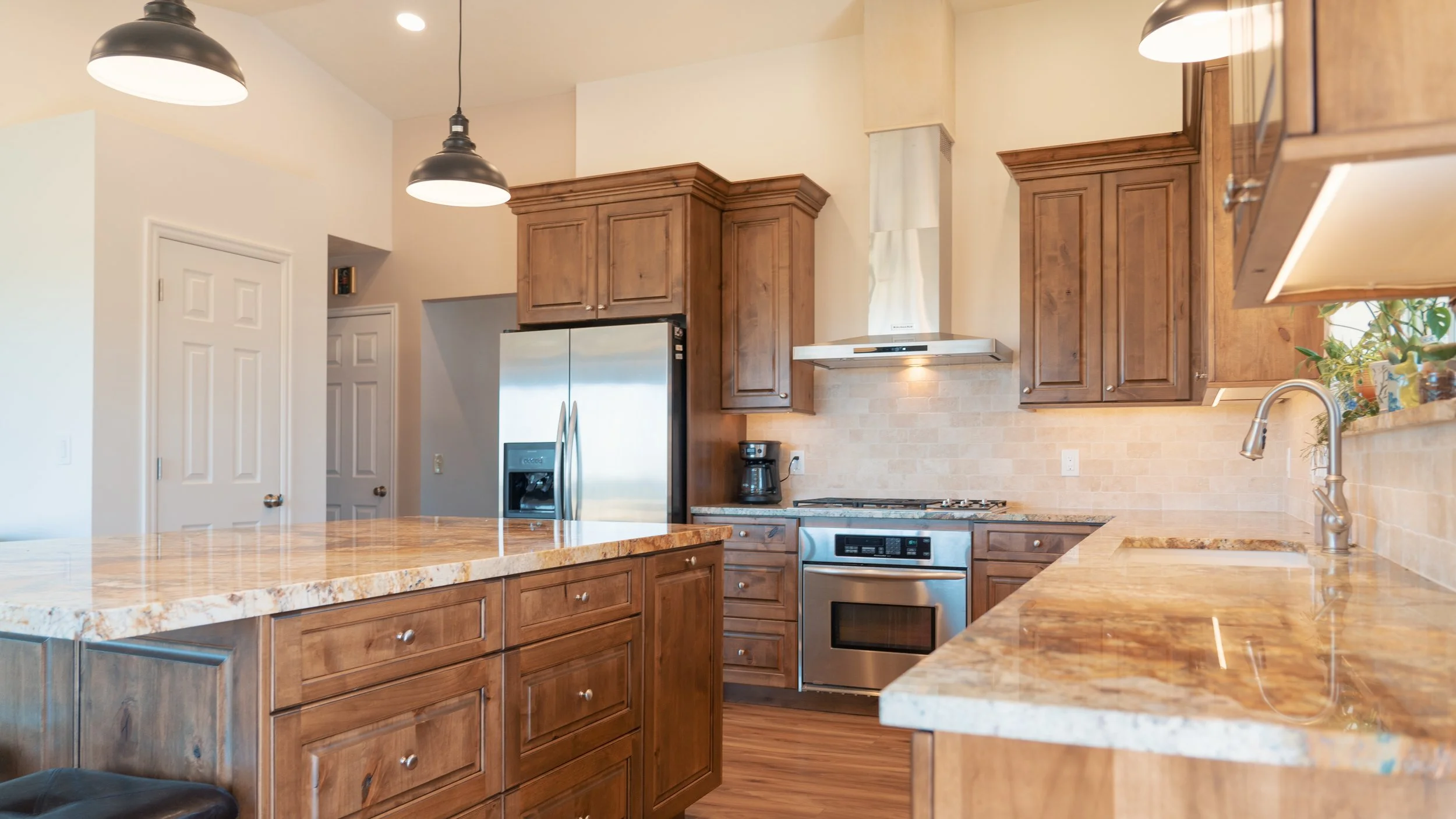 Kitchen with wooden cabinets, granite countertops, stainless steel appliances, and pendant lighting.