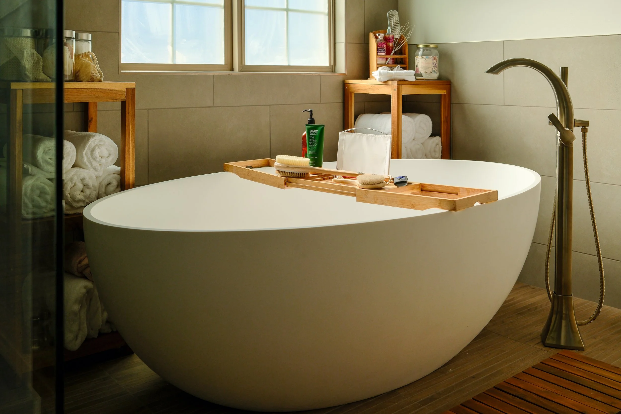 A modern bathtub in a wet room with a floor-mounted faucet