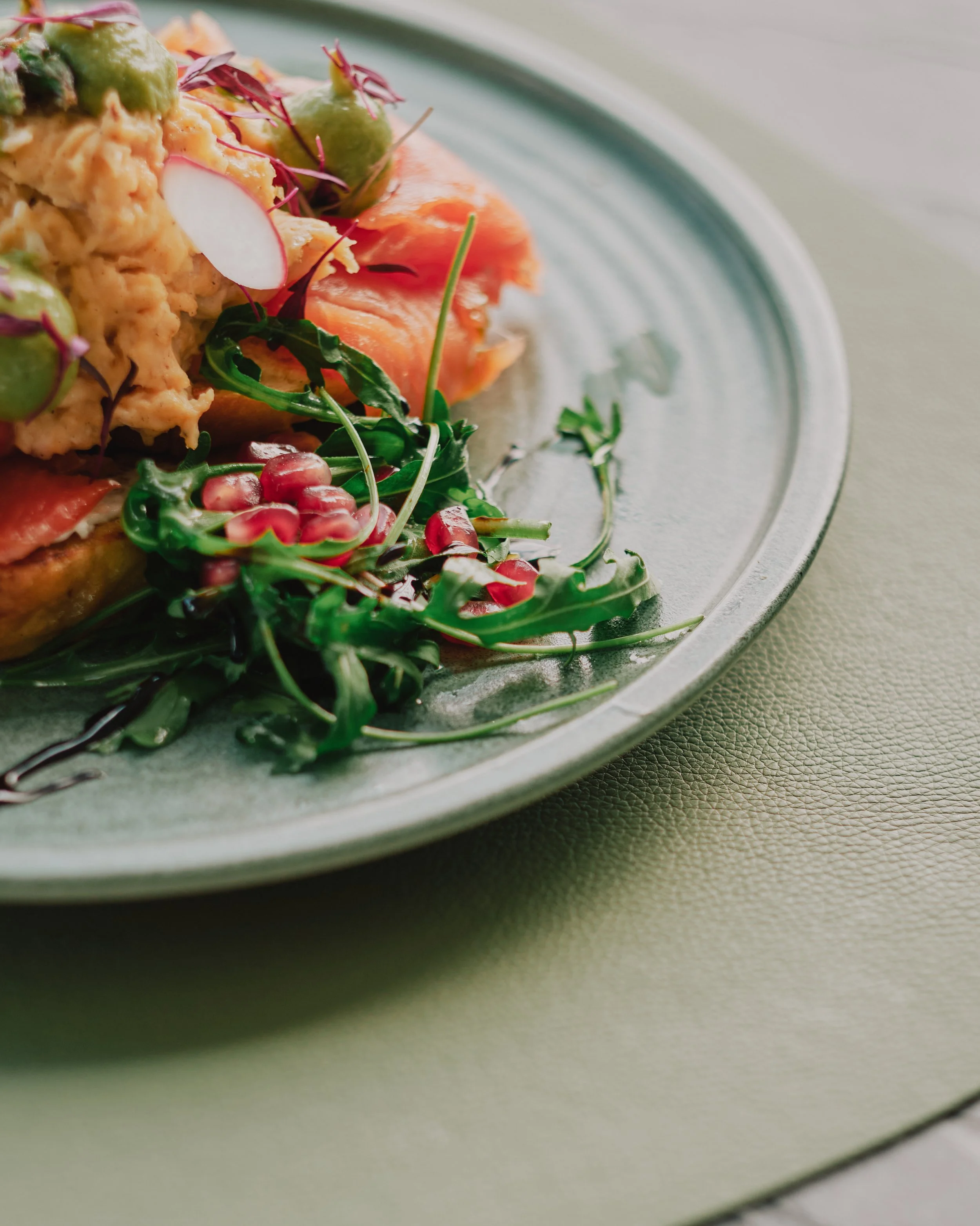 A plate of assorted salad with vegetables, greens, and microgreens on a ceramic dish.