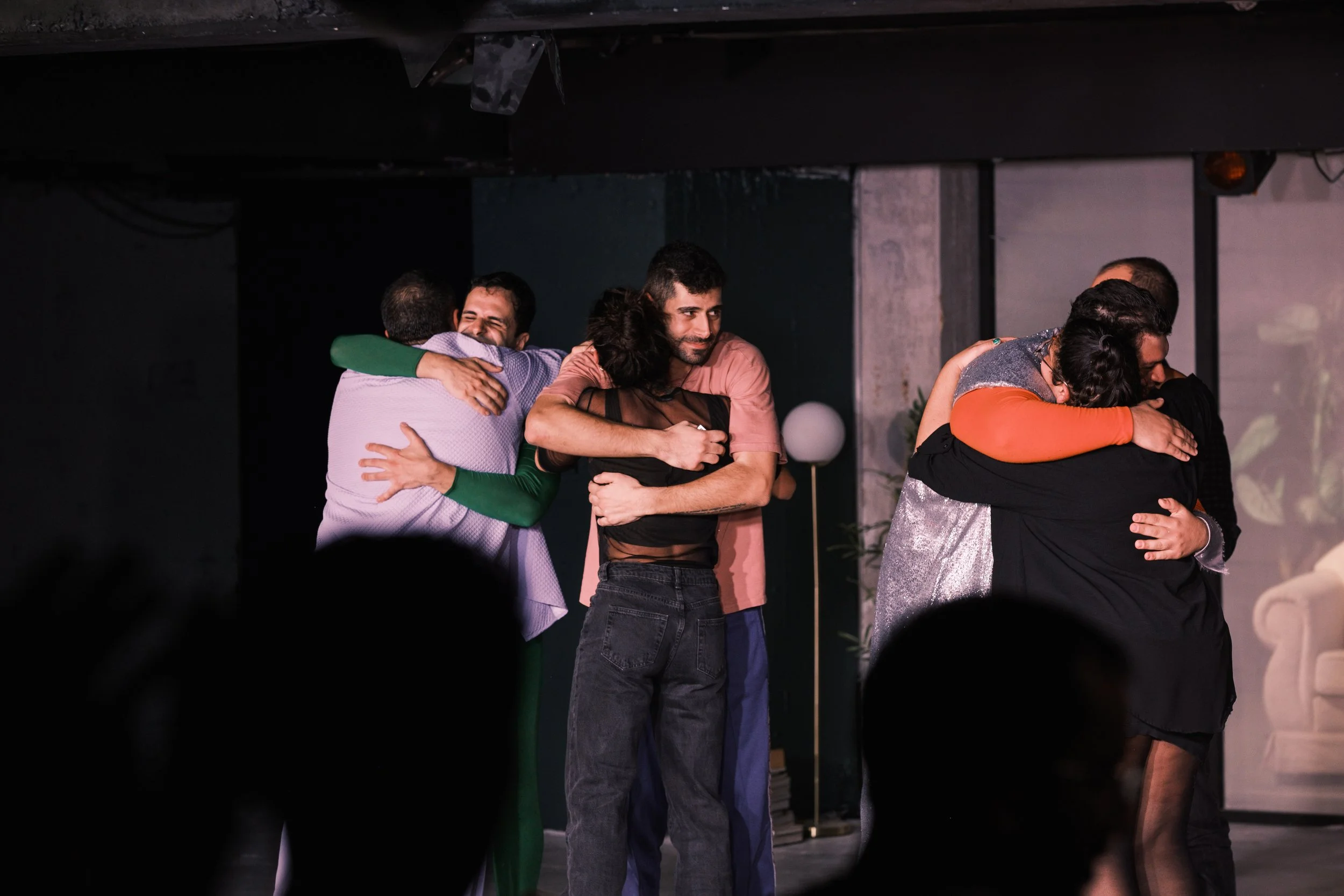 Group of people embracing on stage during a performance or gathering.