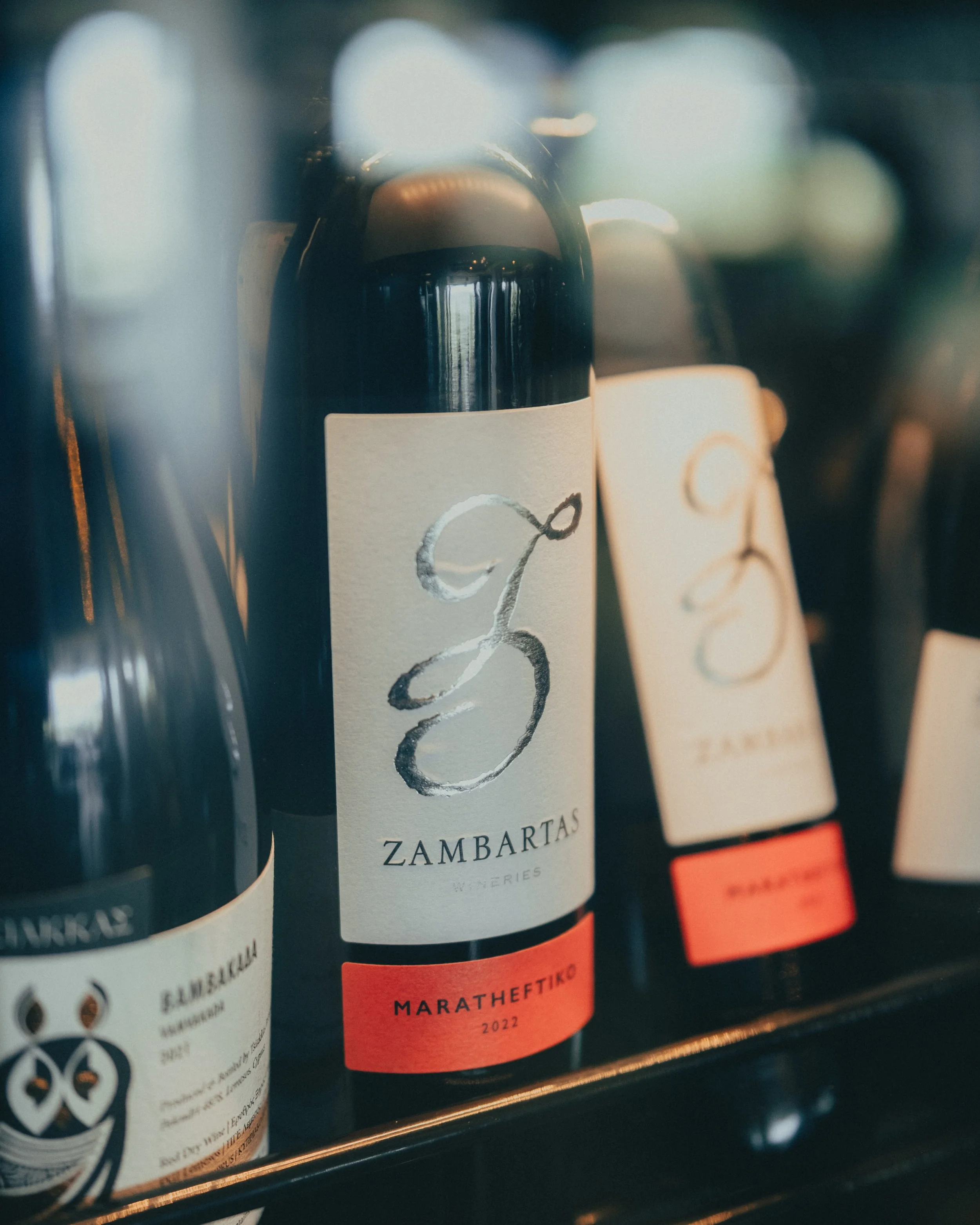 Bottles of wine on a shelf, with a focus on a Zambartas winery bottle labeled 'Maratheftiko 2022'.