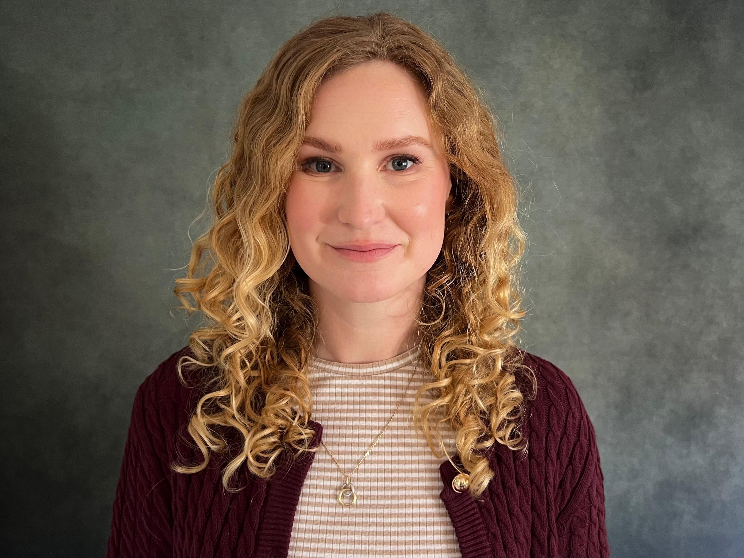 Woman with blond curly hair and stripped t-shirt looking directly