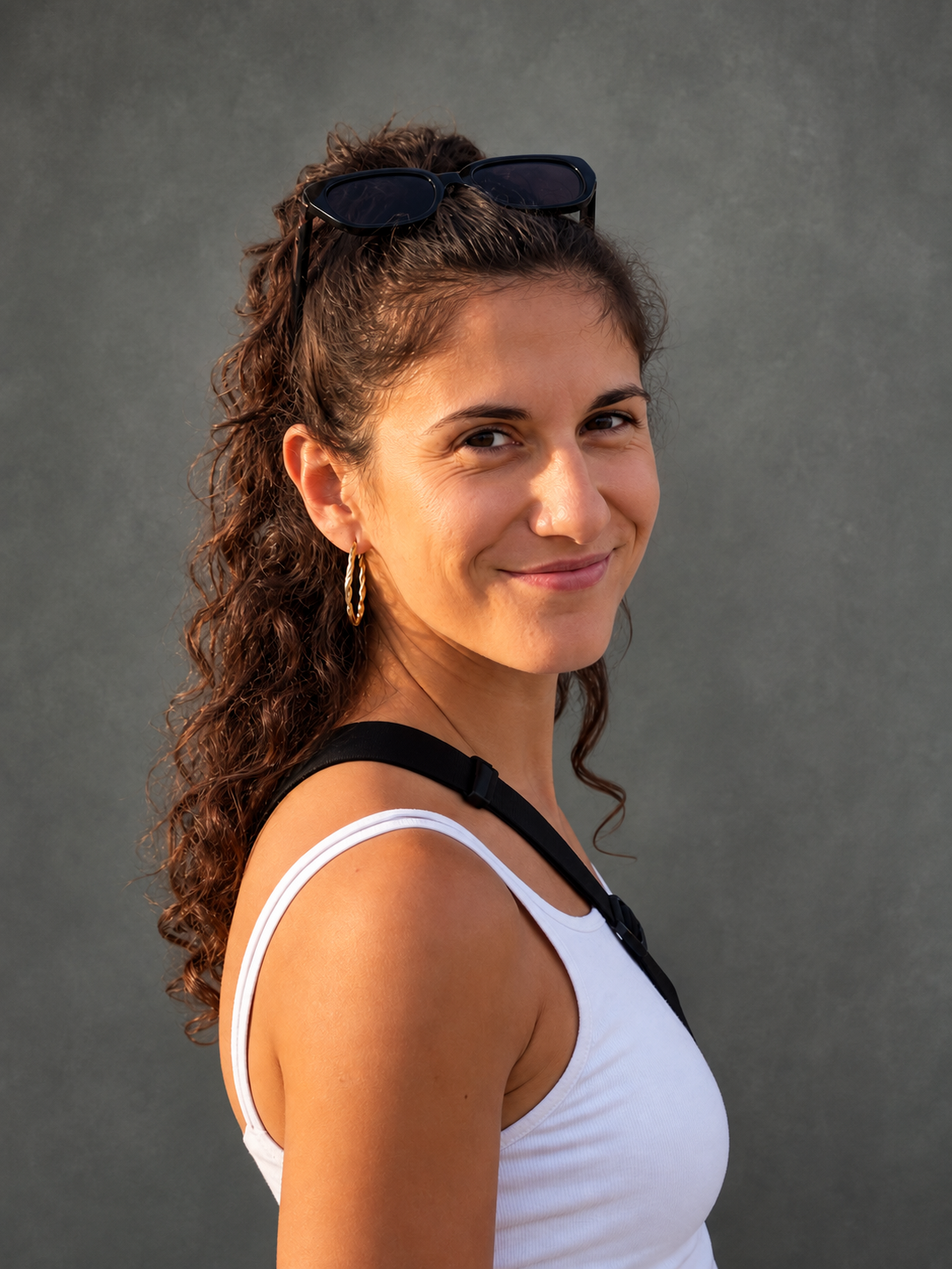 Woman with long curly dark hair with sunglasses on head.