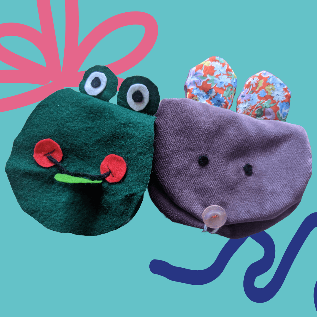 Two fabric puppets: one green with a frog face, the other purple with floral ears on a teal background.