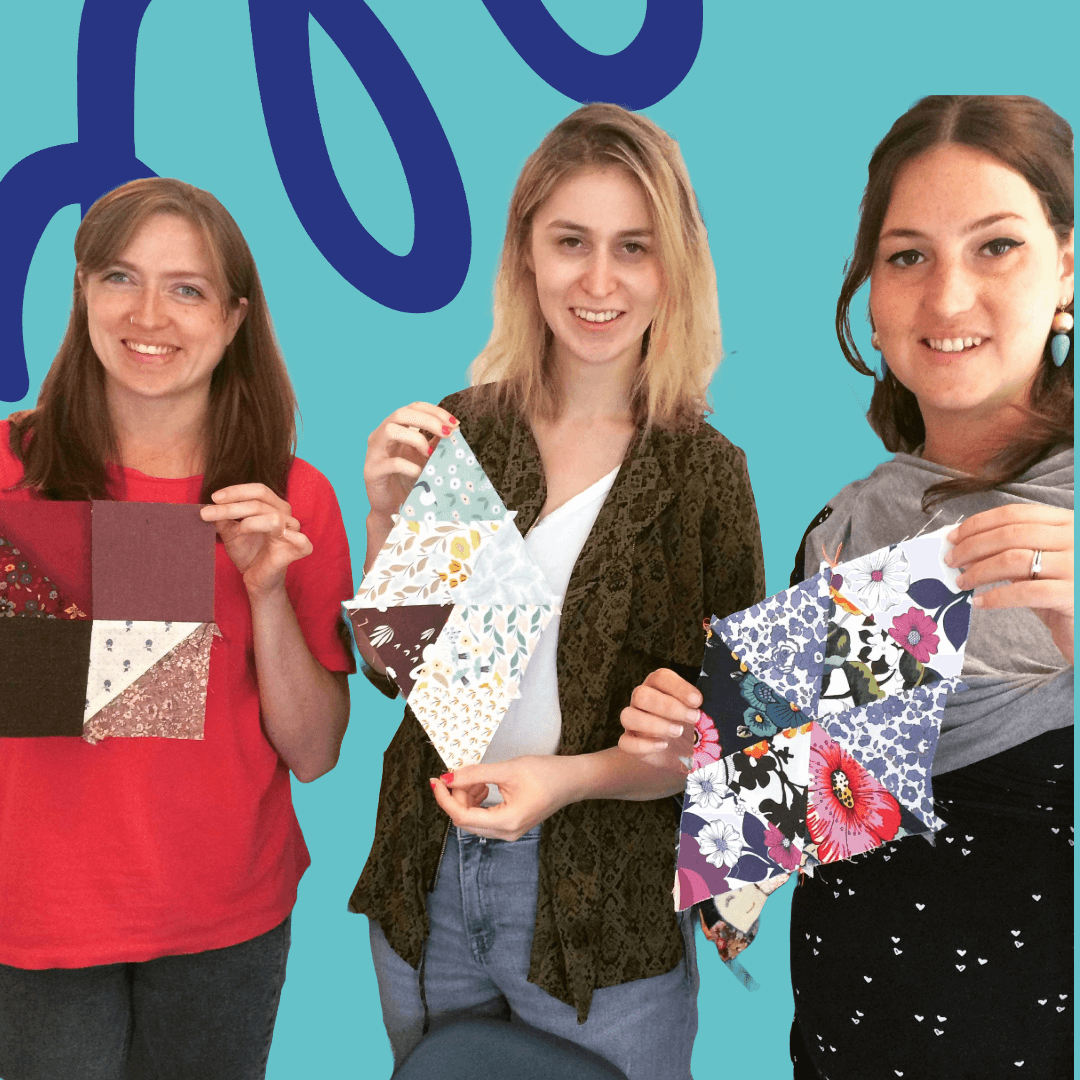 Three women smiling and holding up patchwork blocks