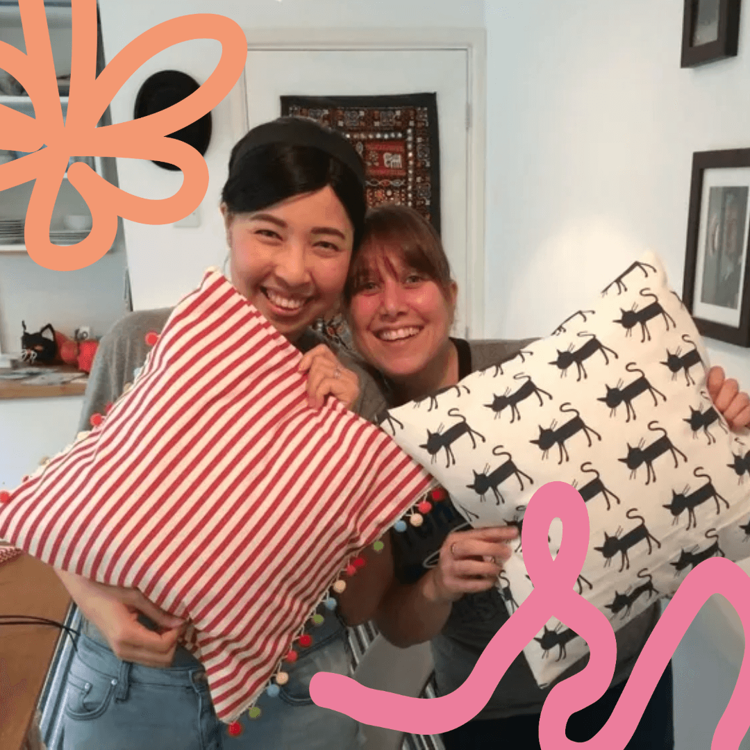 Two people holding up cushions smiling widely