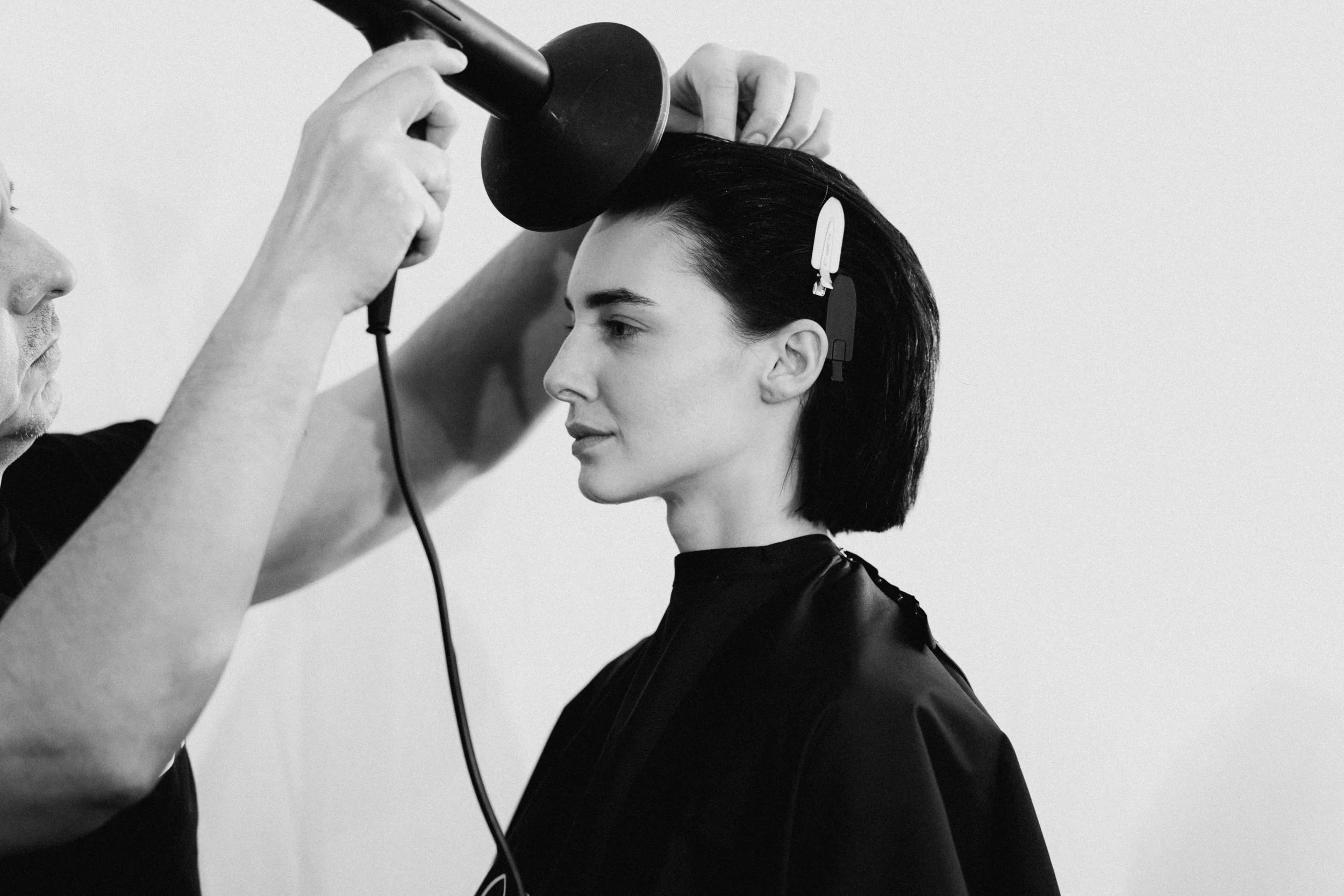 Friseur macht einen Haartest an einer Frau mit schwarz-weißem Haar, die während des Haartestens sitzt.